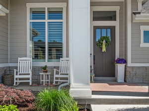 Inviting front entry featuring a paneled door with transom window, stone wainscoting, horizontal siding, and prominent white trim