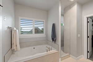 Primary suite/bathroom, Soaking tub with a tile surround and a window featuring plantation shutters