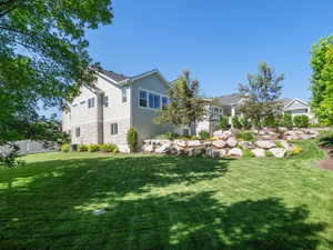 Expansive rear lawn featuring a tiered landscape design with boulders and established plantings