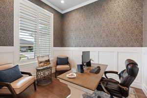 Room featuring wood-finish flooring, intricate patterned wallpaper, white board and batten wall paneling, and white plantation shutters