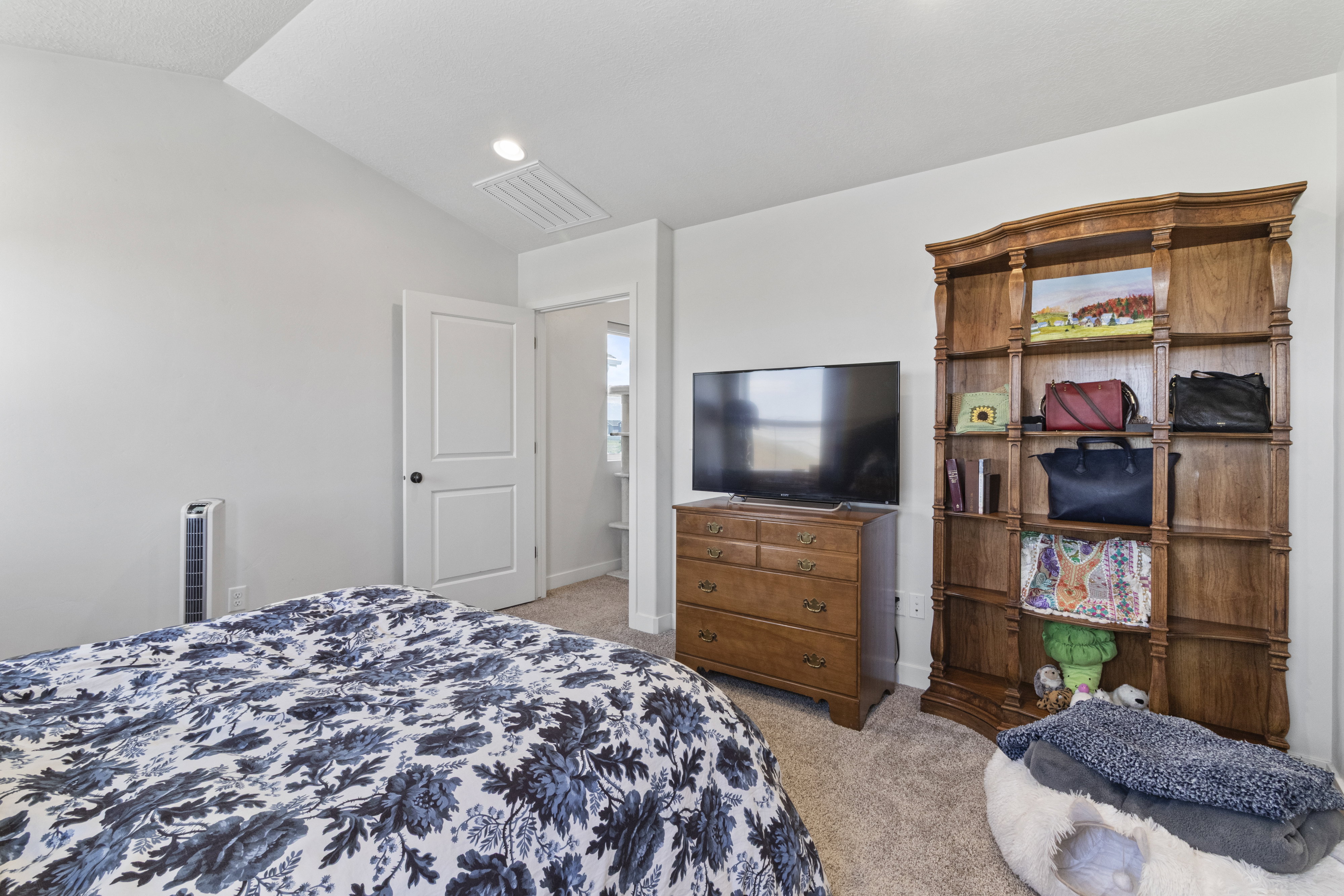 Carpeted room featuring a vaulted ceiling with an overhead light fixture, white walls, and a two-panel interior door