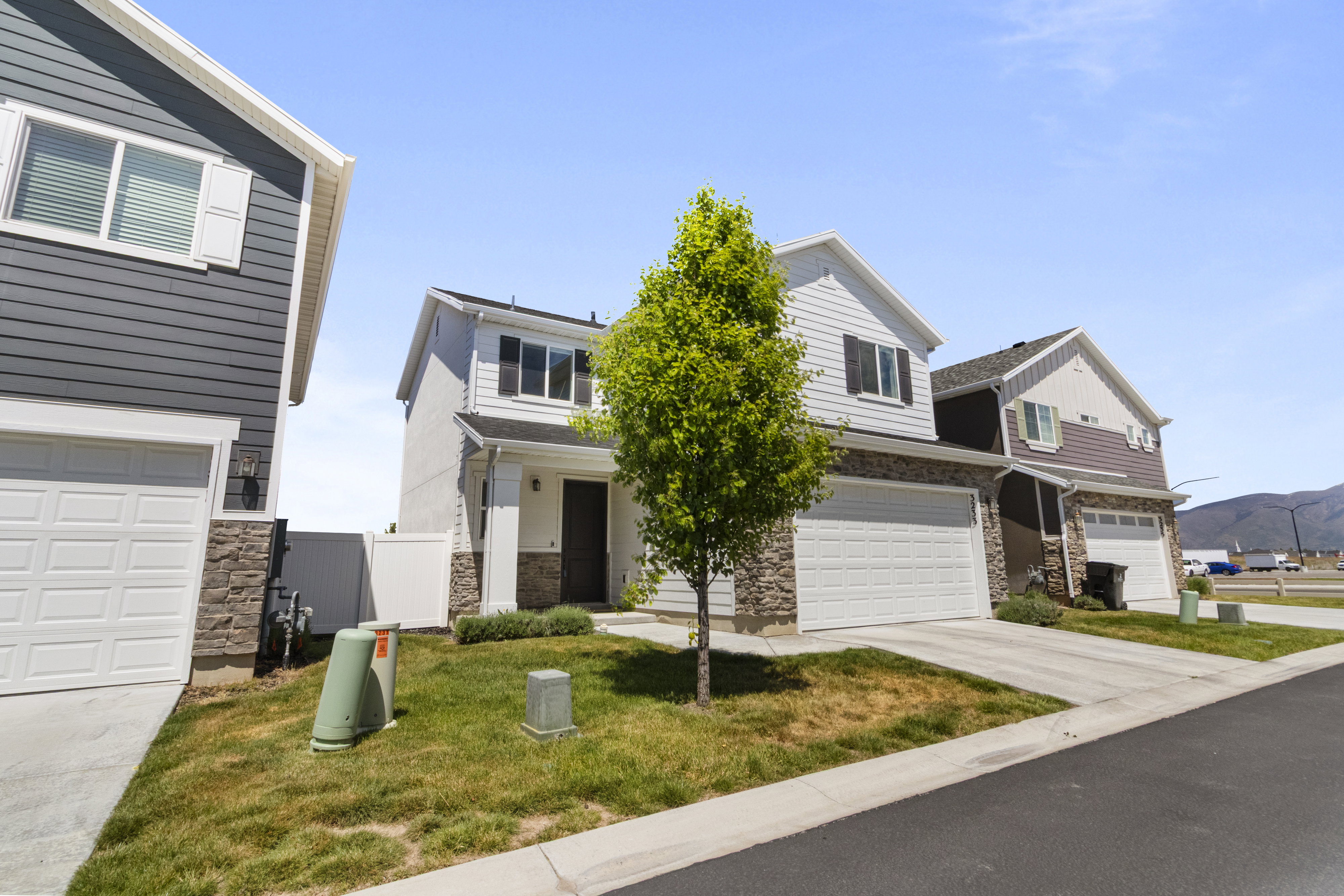 Two-story residence featuring white siding and stone veneer accents
