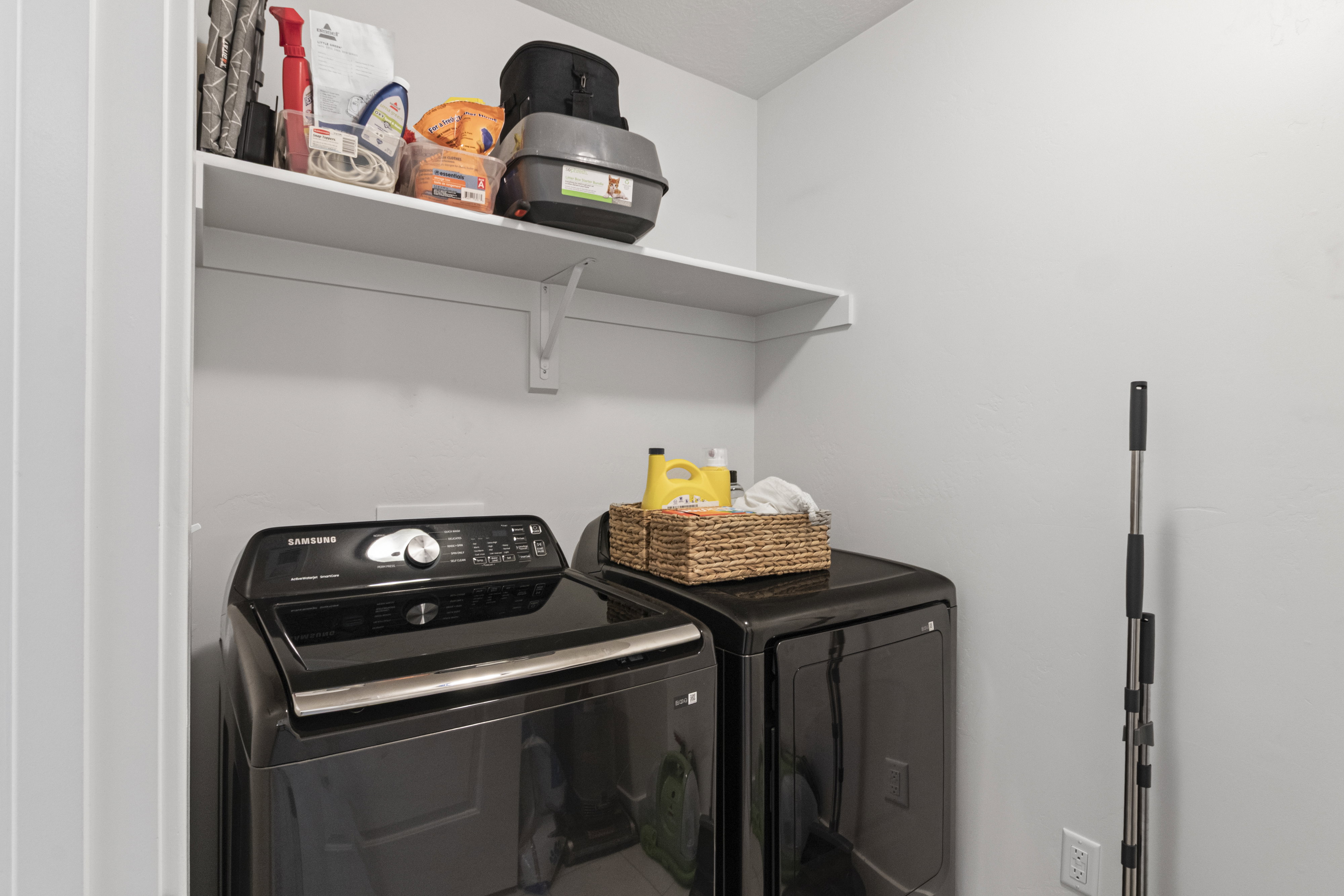 Dedicated laundry area featuring a white wall shelf, light walls, and light-colored flooring