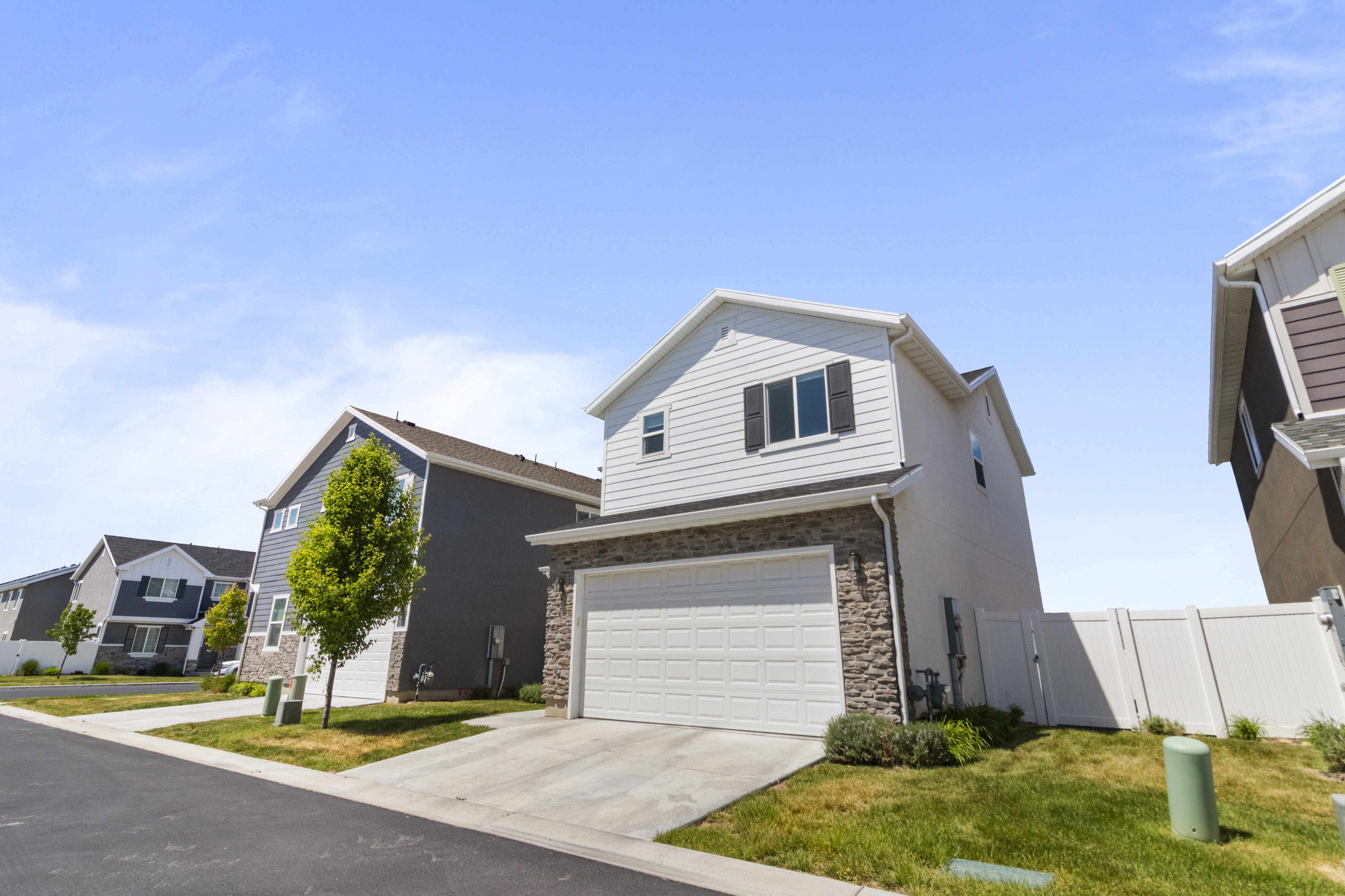 Two-story property featuring light-colored siding and stone veneer accents