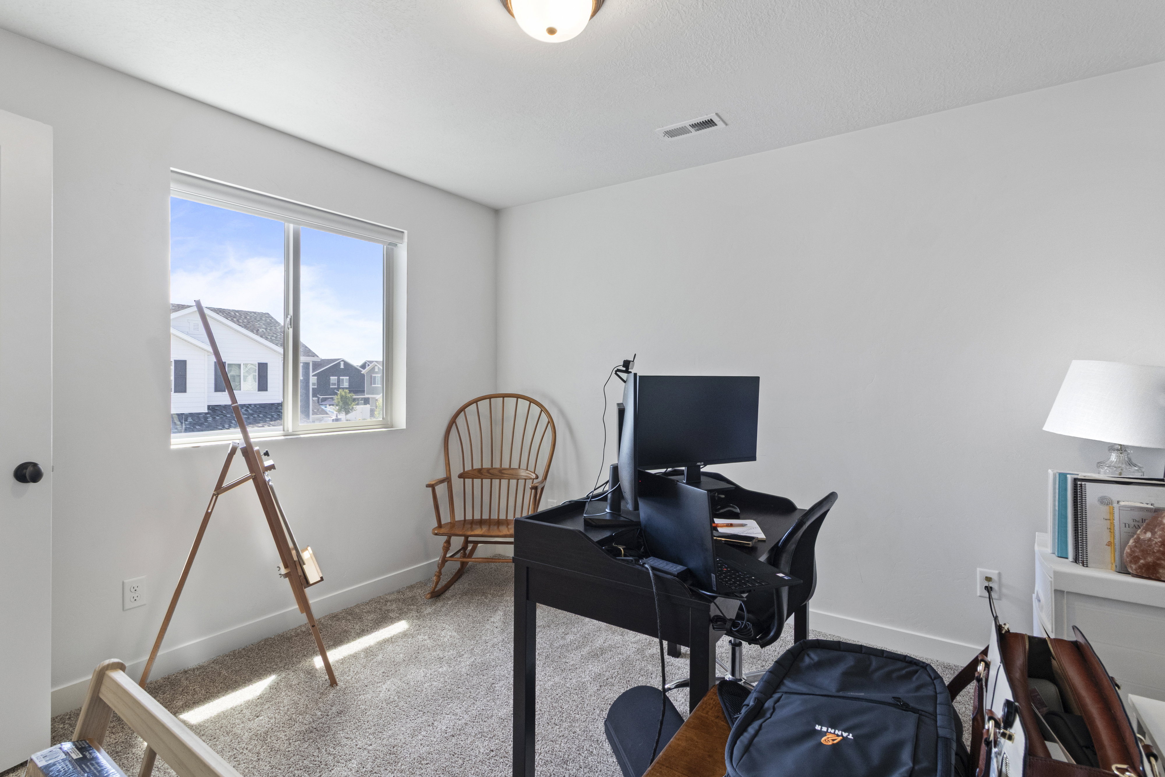 Bright interior room with a large window, light-colored walls, and textured carpeting