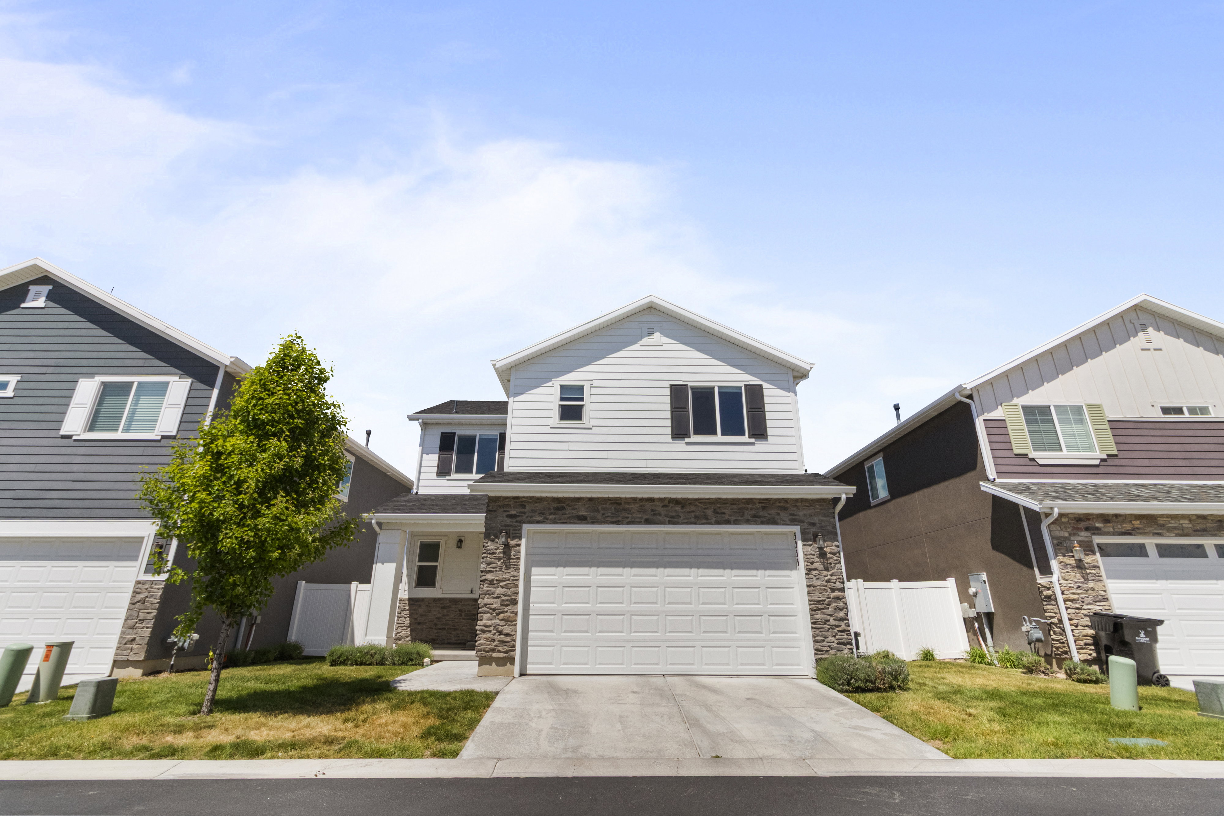 Two-story residence featuring a stone and siding facade, an attached garage with a white door, and a concrete driveway