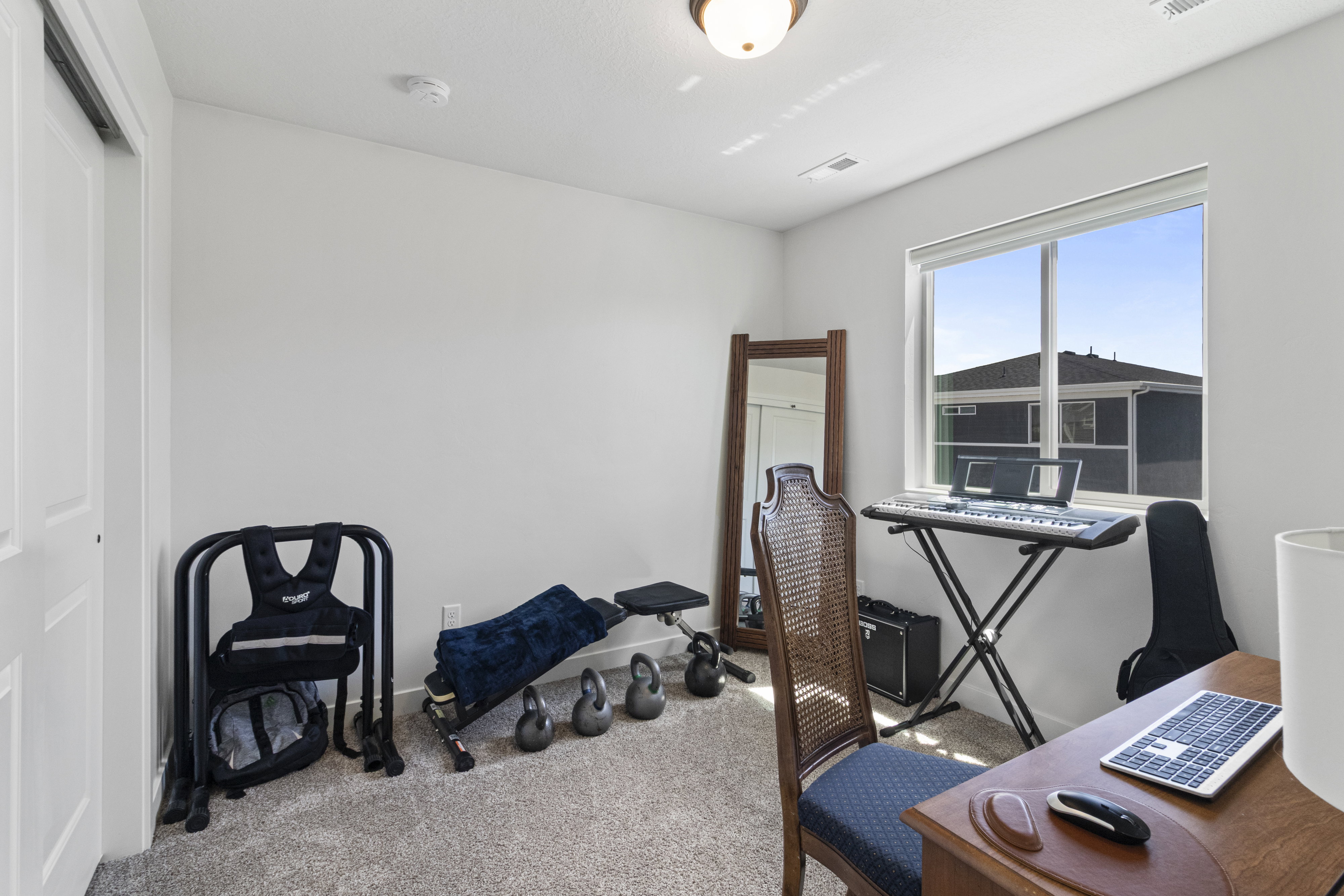 Bright room featuring a large window, neutral carpeting, white walls, and a ceiling light fixture