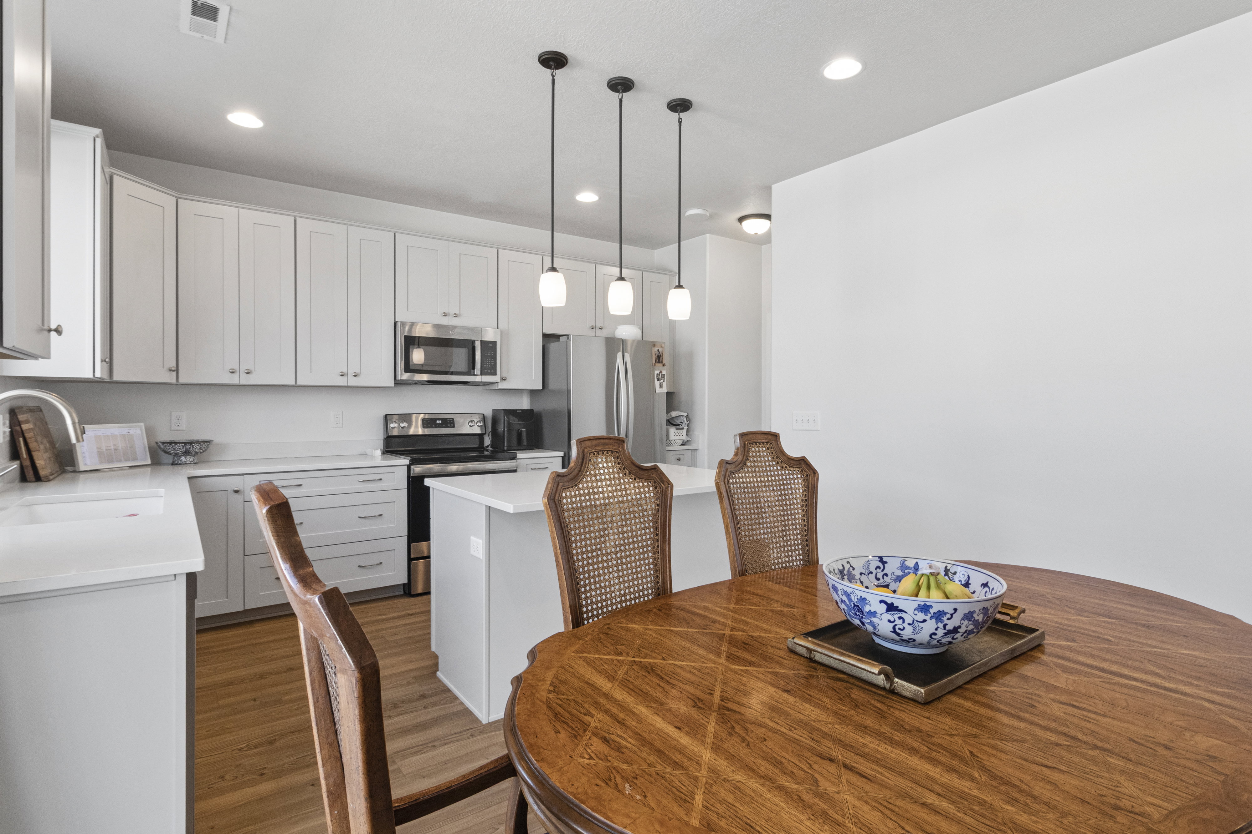 Modern kitchen featuring white cabinetry, stainless steel appliances, and a central island with pendant lighting