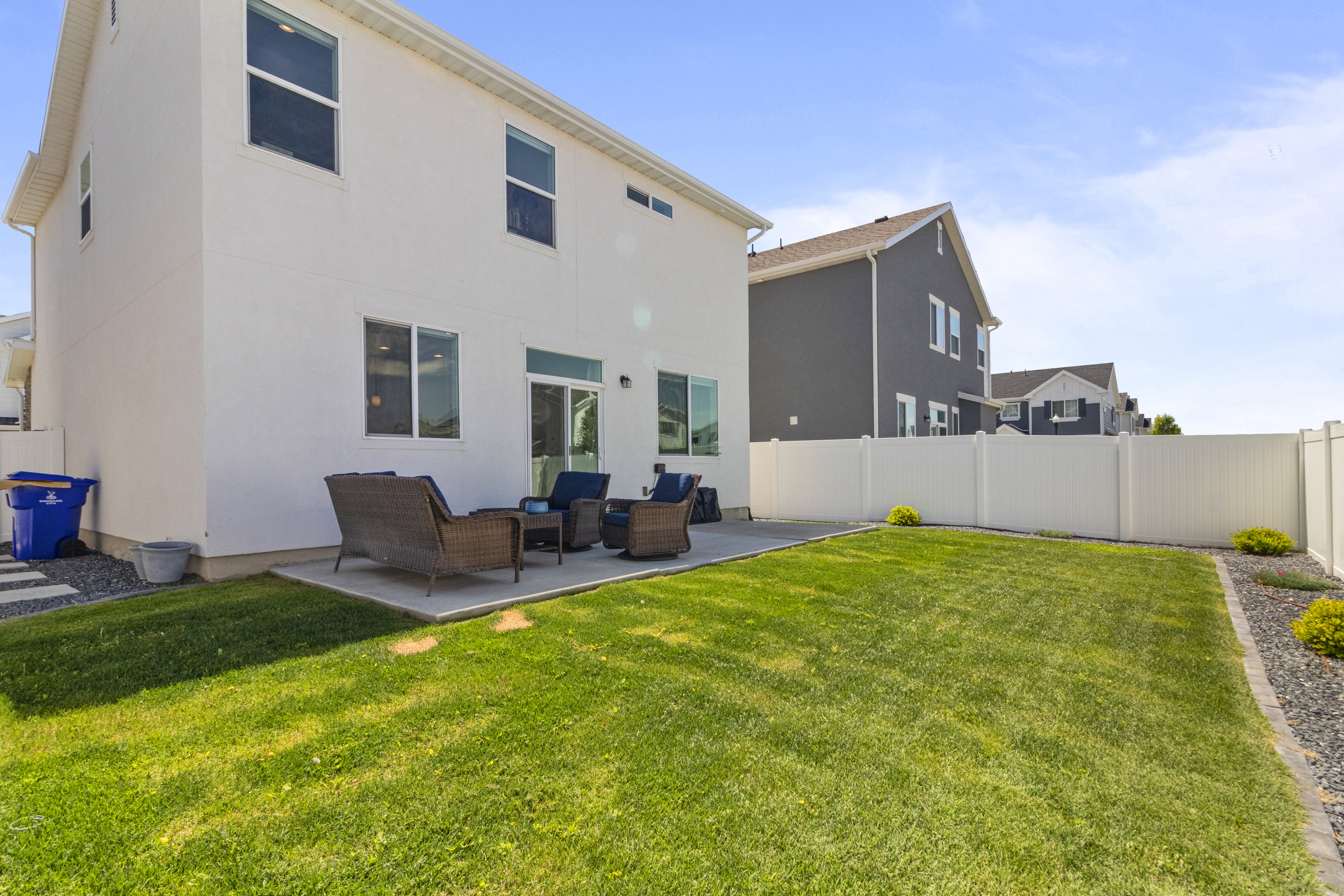 Expansive rear yard featuring a concrete patio, green lawn, and gravel landscaping