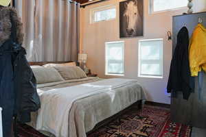 Wood-finish flooring with an area rug, complemented by a bed frame with a wood headboard