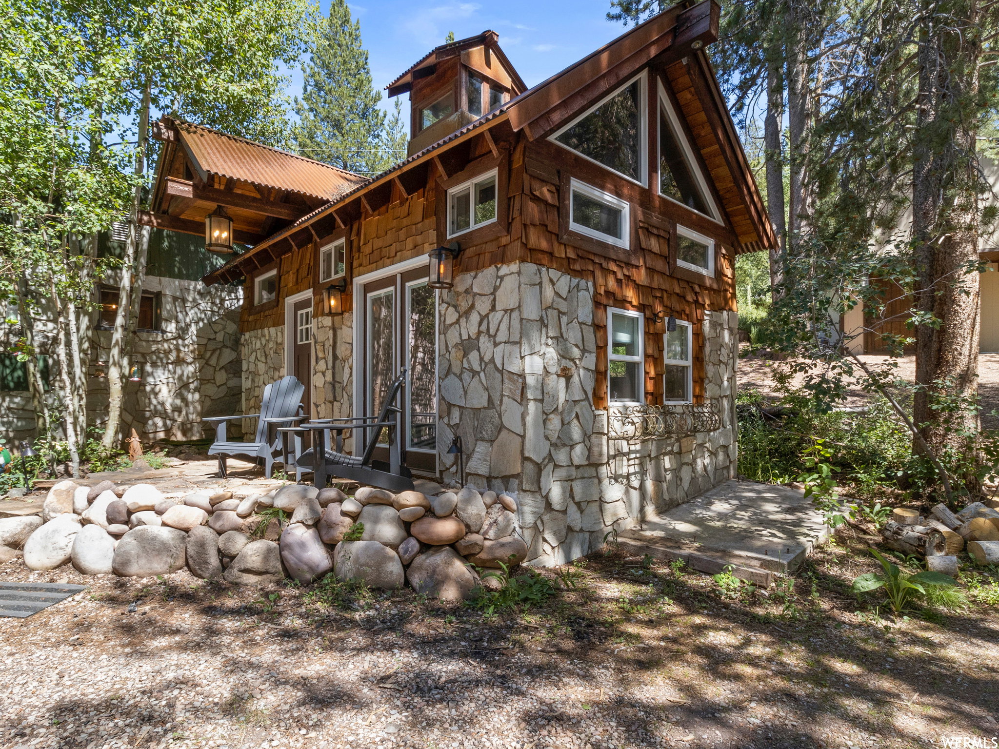 Stone and wood-shingle exterior featuring a corrugated metal roof and multiple windows
