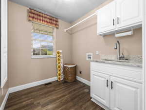 Utility area featuring wood-finish flooring, a single window with blinds, white cabinetry, a light-toned countertop, and a stainless steel sink with a gooseneck faucet