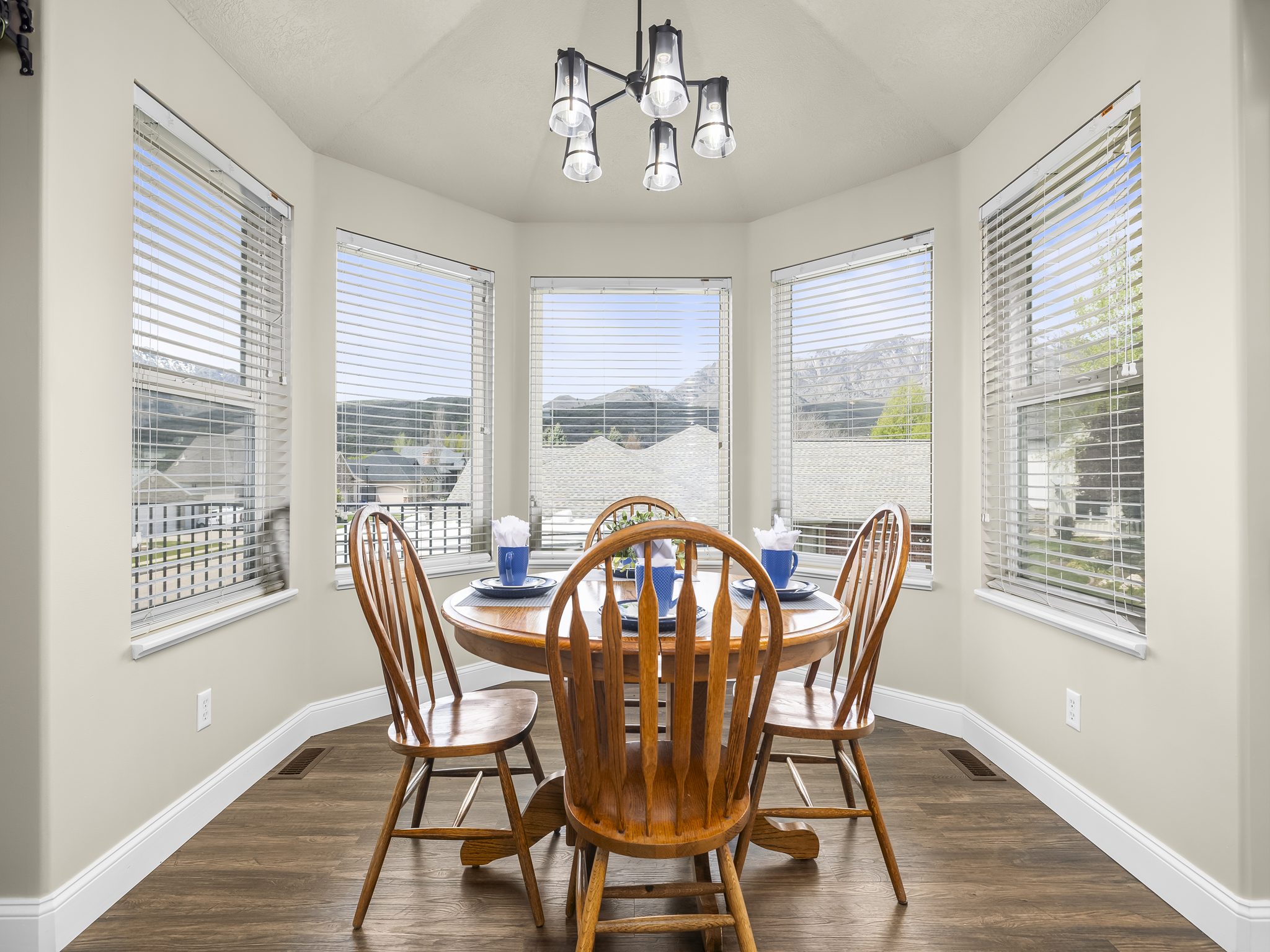 Bay window dining area featuring wood-finish flooring, light neutral wall paint, and a contemporary multi-light fixture