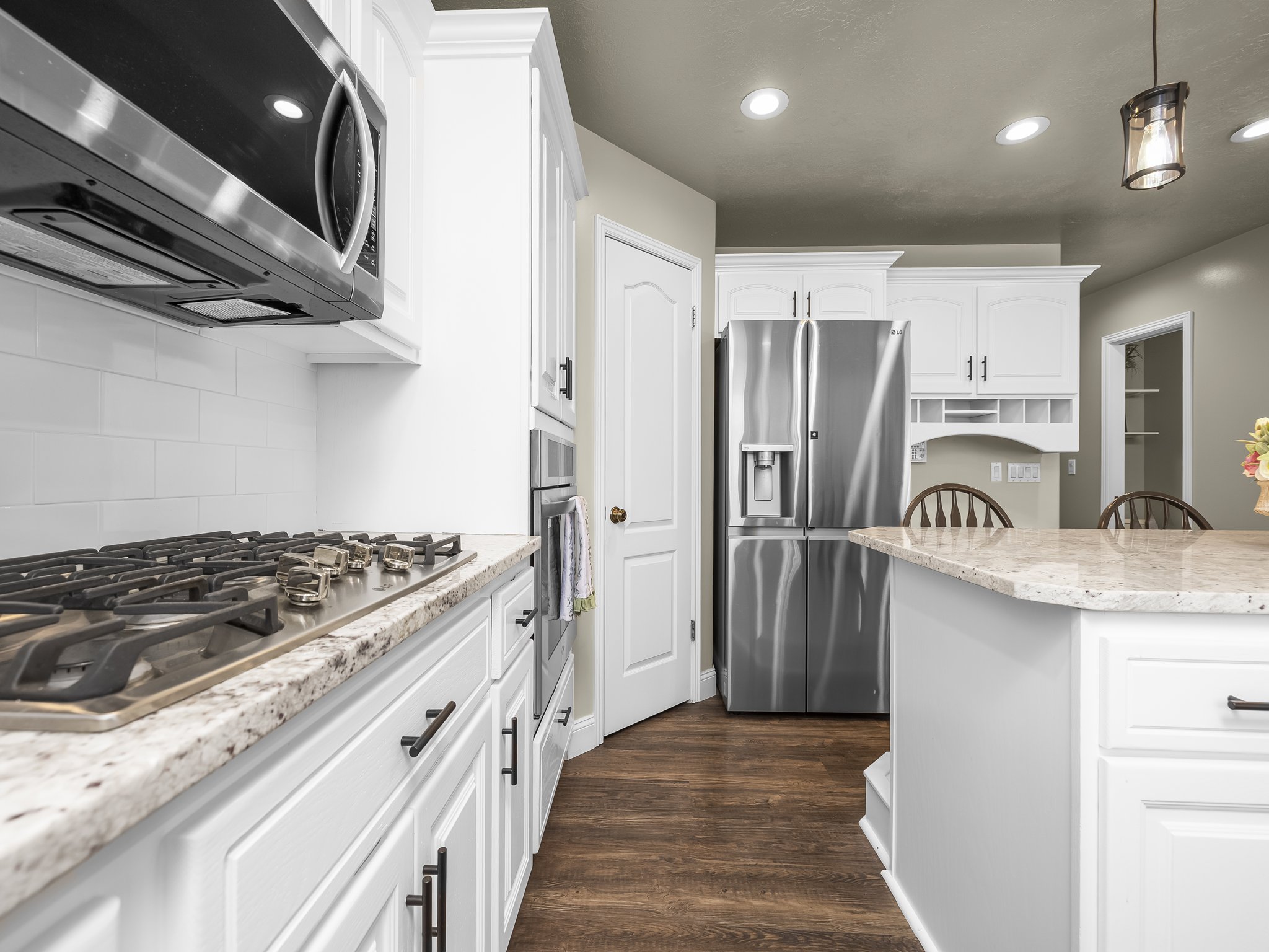 Kitchen featuring white cabinetry, stainless steel appliances, a gas cooktop, stone countertops, and wood-finish flooring