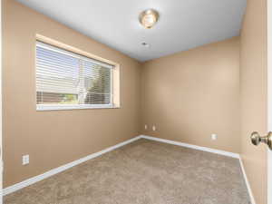 Carpeted room featuring a single window with horizontal blinds, neutral-toned walls, white trim, and a ceiling-mounted light fixture