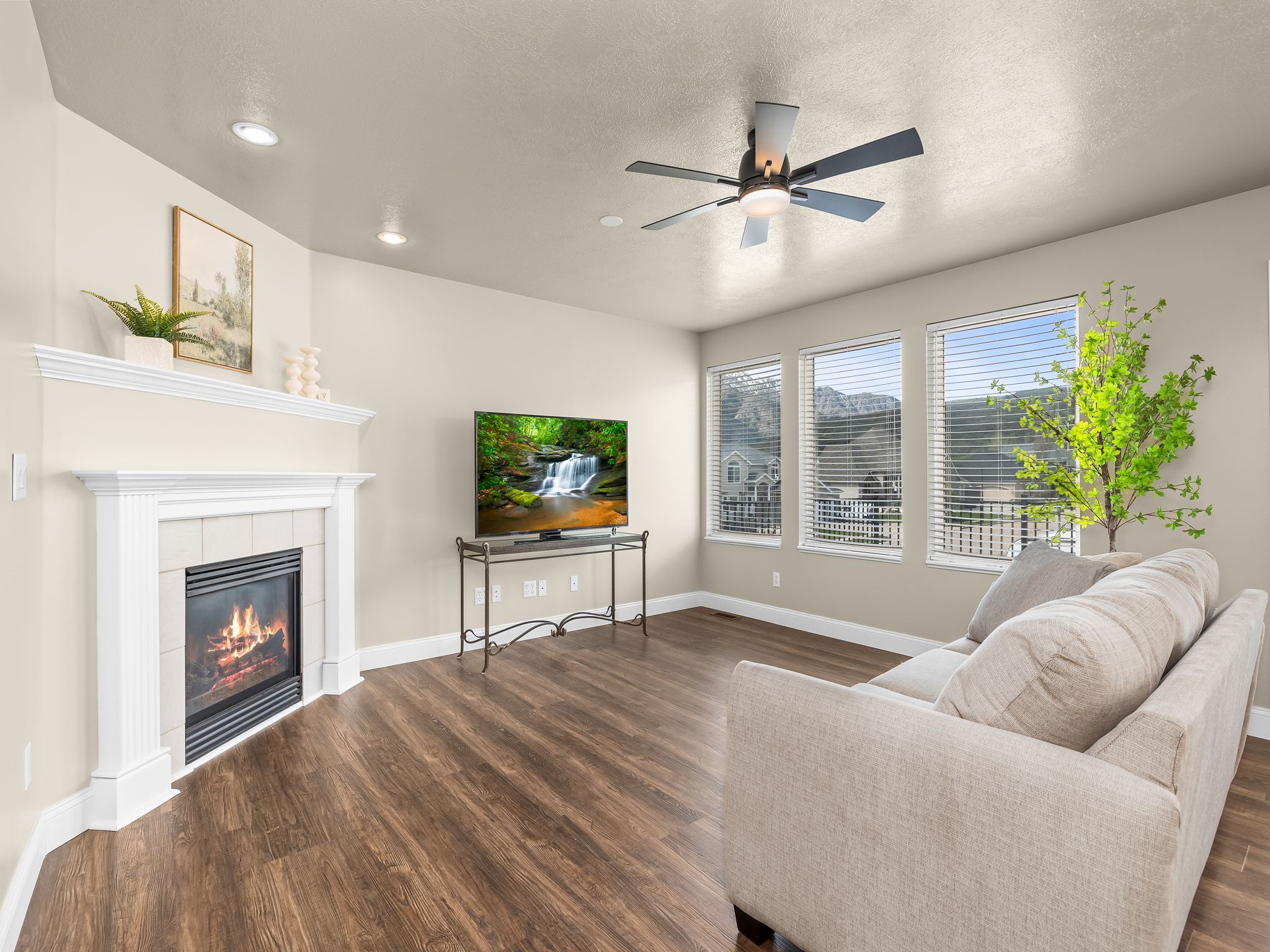 Living area featuring wood-finish flooring and a corner fireplace with a white mantel and tiled surround