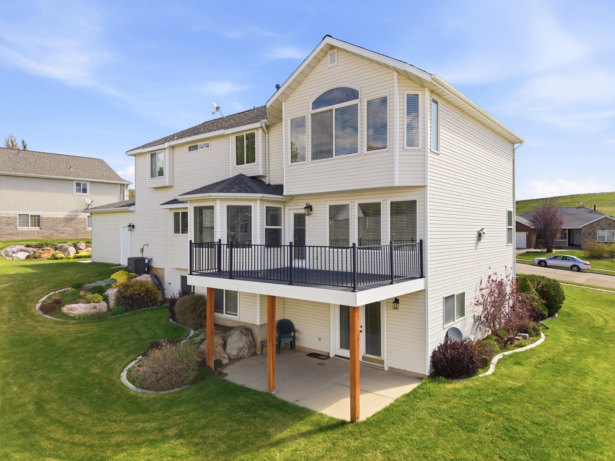 Multi-level rear exterior featuring a raised deck with black railings, a walk-out patio, and multiple windows