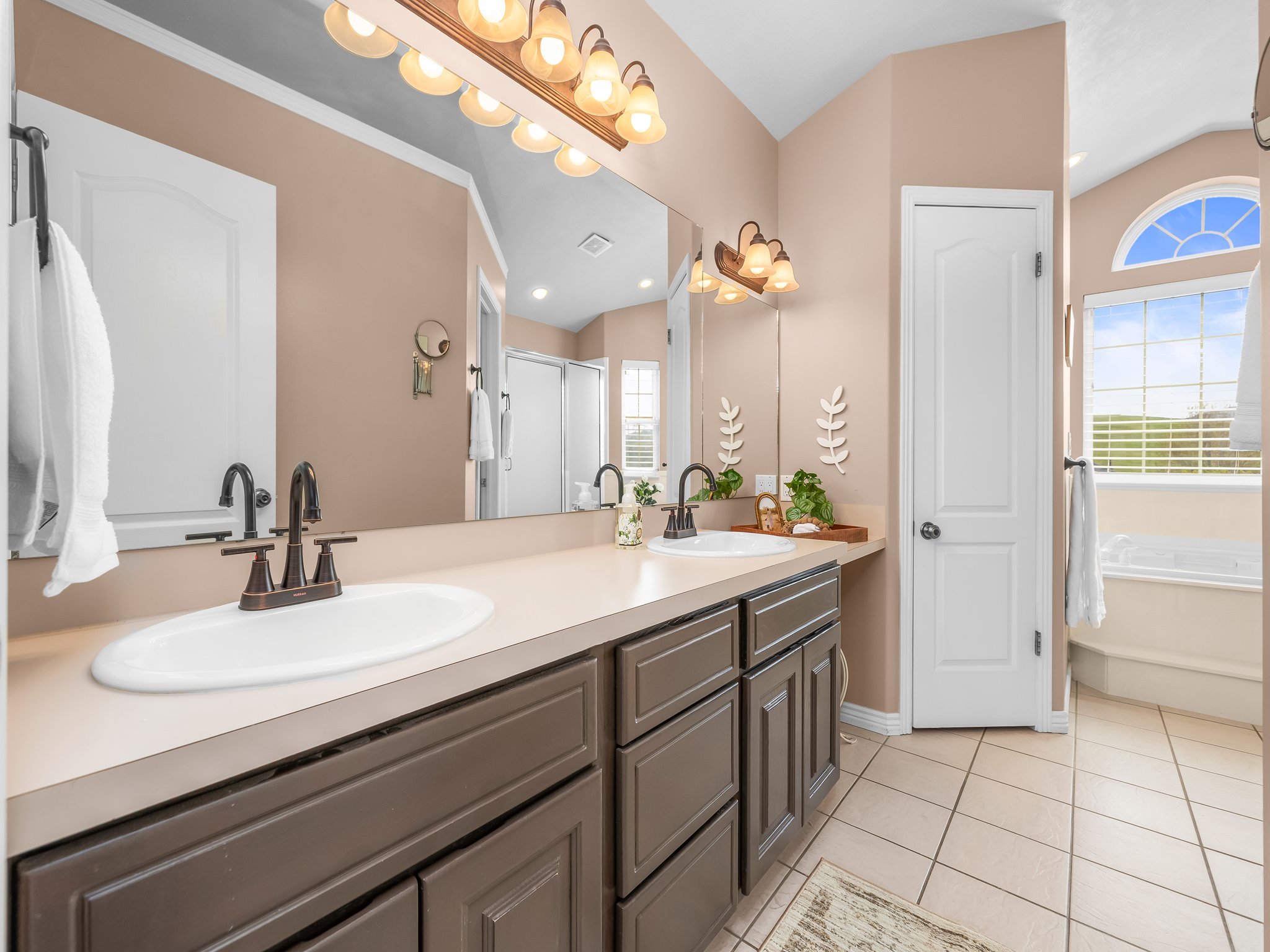 Double vanity with integrated sinks and bronze-finish faucets set against a full-width mirror