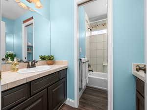 Bathroom featuring a dark wood-finish vanity with an integrated basin sink, tiled countertop, and bronze-finish hardware