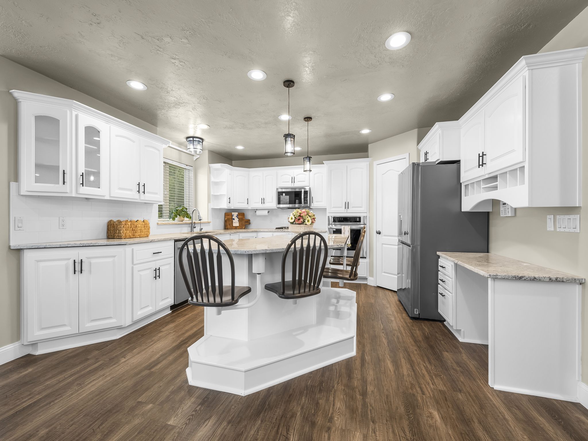 Kitchen featuring a central island with integrated seating, white cabinetry, wood-finish flooring, recessed lighting, and a white subway tile backsplash