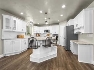 Kitchen featuring a central island with integrated seating, white cabinetry, wood-finish flooring, recessed lighting, and a white subway tile backsplash