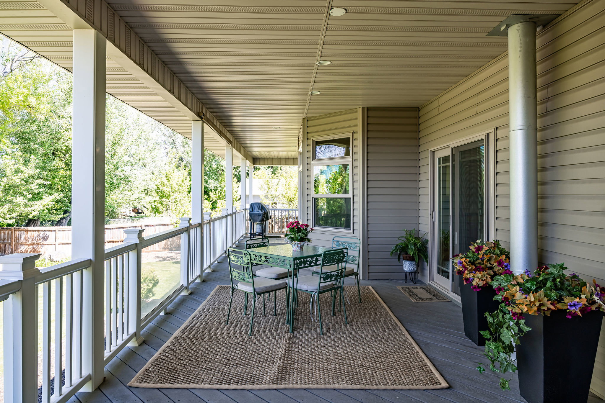 Expansive covered porch featuring a composite deck, white baluster railing, recessed lighting, and direct access through sliding glass doors