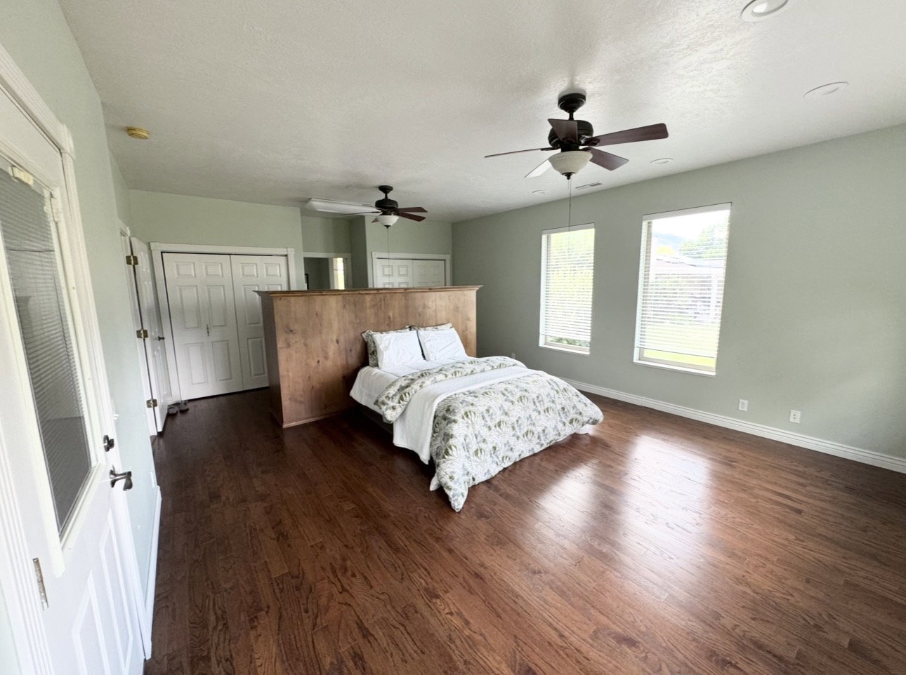 Spacious room featuring rich wood-finish flooring, multiple windows with blinds, and recessed lighting