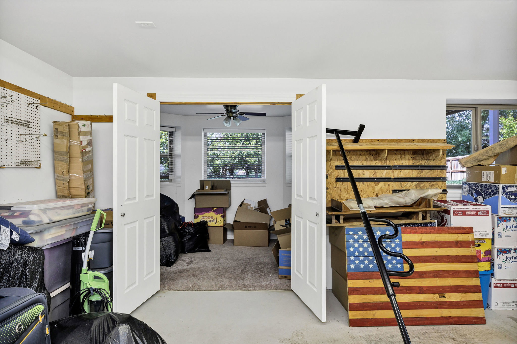 Carpeted room featuring a ceiling fan, two windows with blinds, and white double doors