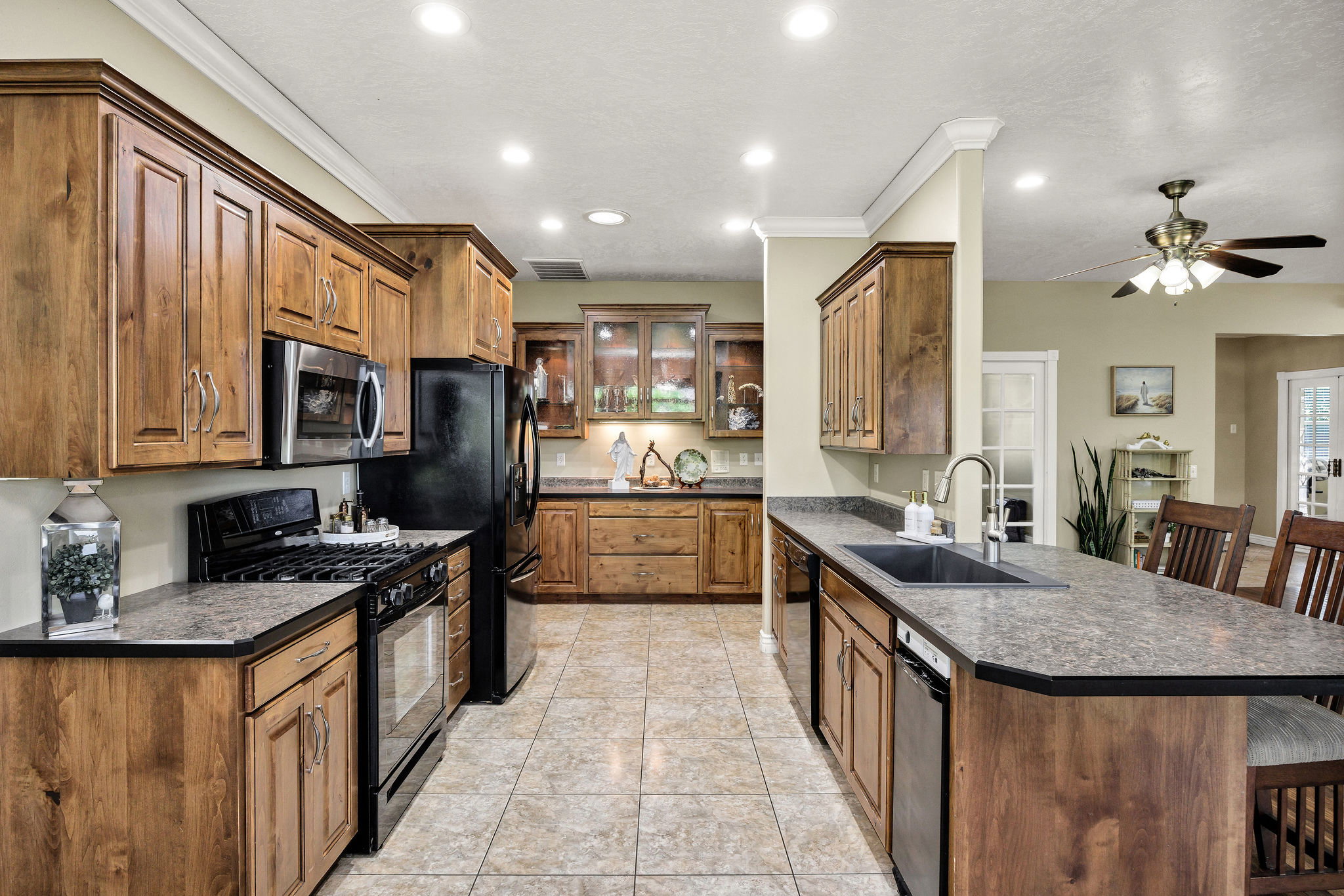 Kitchen featuring ample wood cabinetry, tile flooring, recessed lighting, and a kitchen island with a built-in sink and seating
