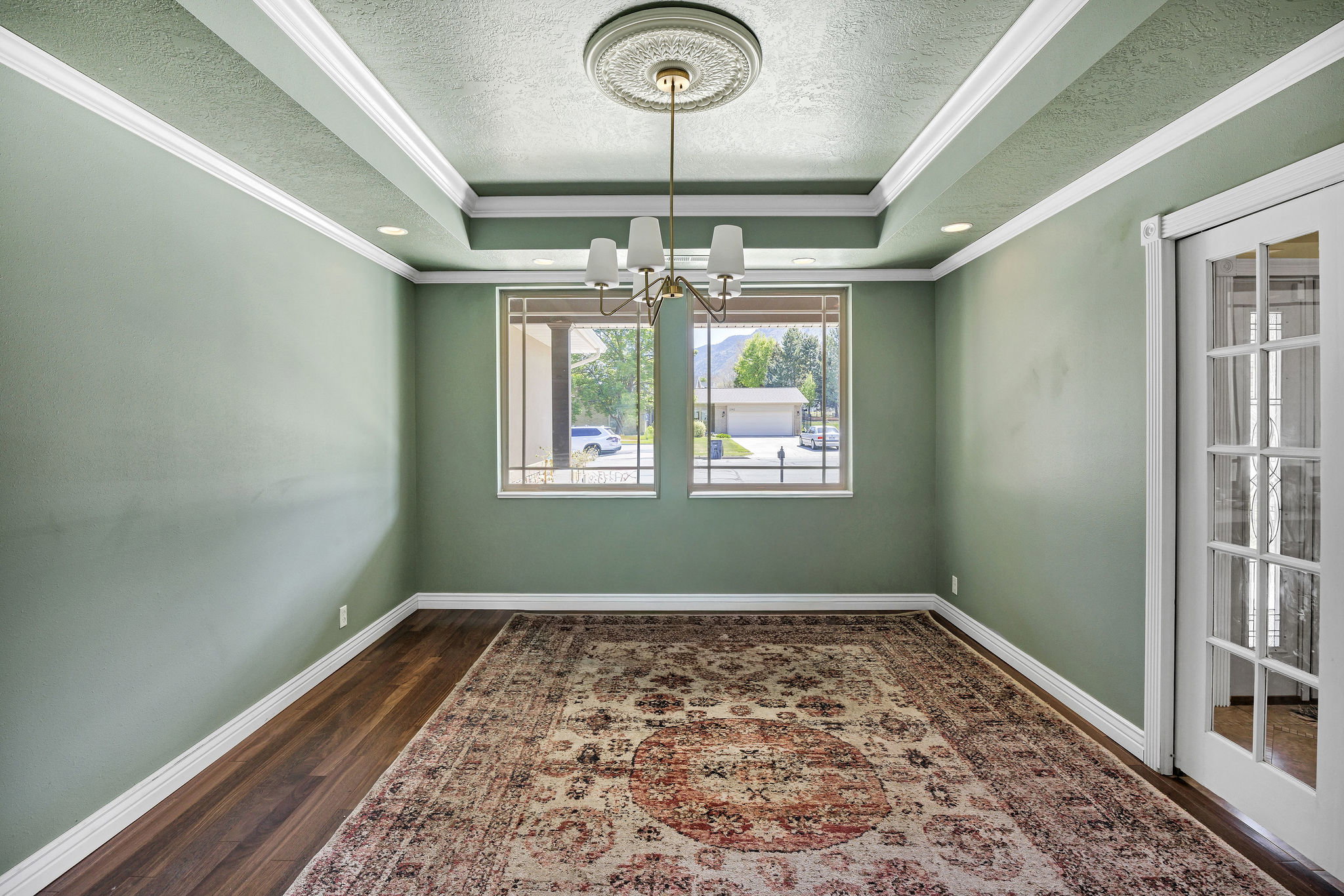 Formal room featuring a tray ceiling with recessed lighting and a central chandelier
