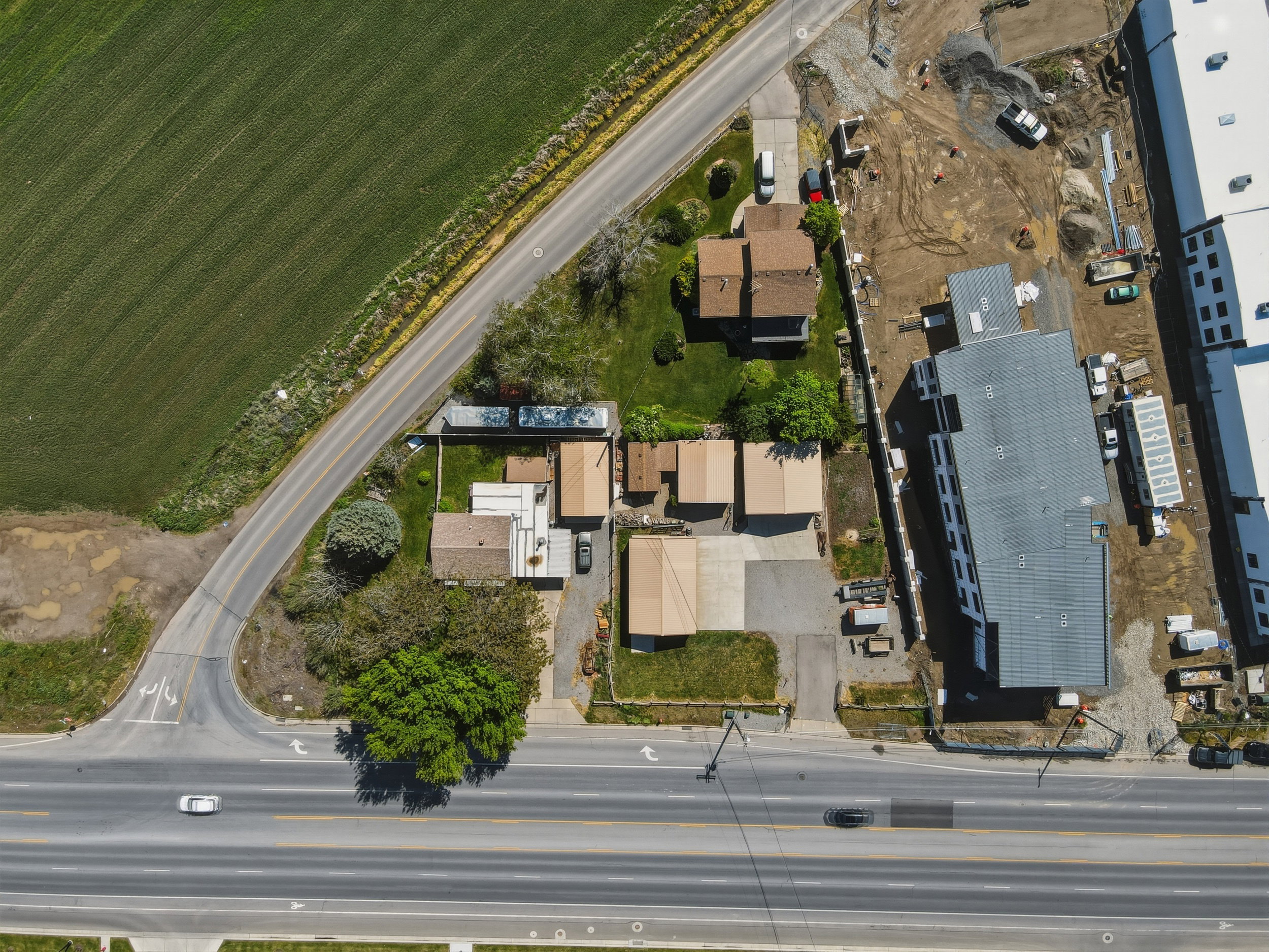 Aerial overview of the property, featuring a paved surface, varied rooflines, and surrounding green spaces