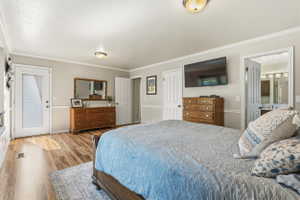 Bedroom featuring wood-finish flooring, neutral wall tones, crown molding, and a built-in window bench