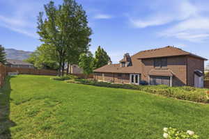 Expansive backyard featuring a manicured lawn, mature trees, and a wooden privacy fence