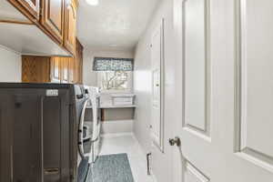 Dedicated laundry room featuring upper wood cabinetry, a built-in folding shelf, and a window for natural light