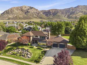 Brick two-story residence featuring a brown shingle roof and a prominent two-car garage