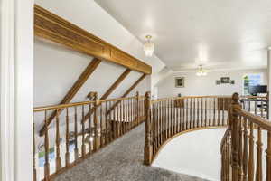 Upper level landing featuring light-toned carpeting and wood railings