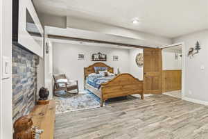 Spacious room featuring wood-finish flooring, a recessed lighting fixture, and a decorative fireplace with a stacked stone facade