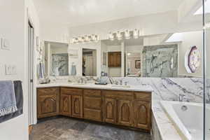 Dual basin vanity with wood cabinetry and white countertop, featuring a large mirror and overhead lighting