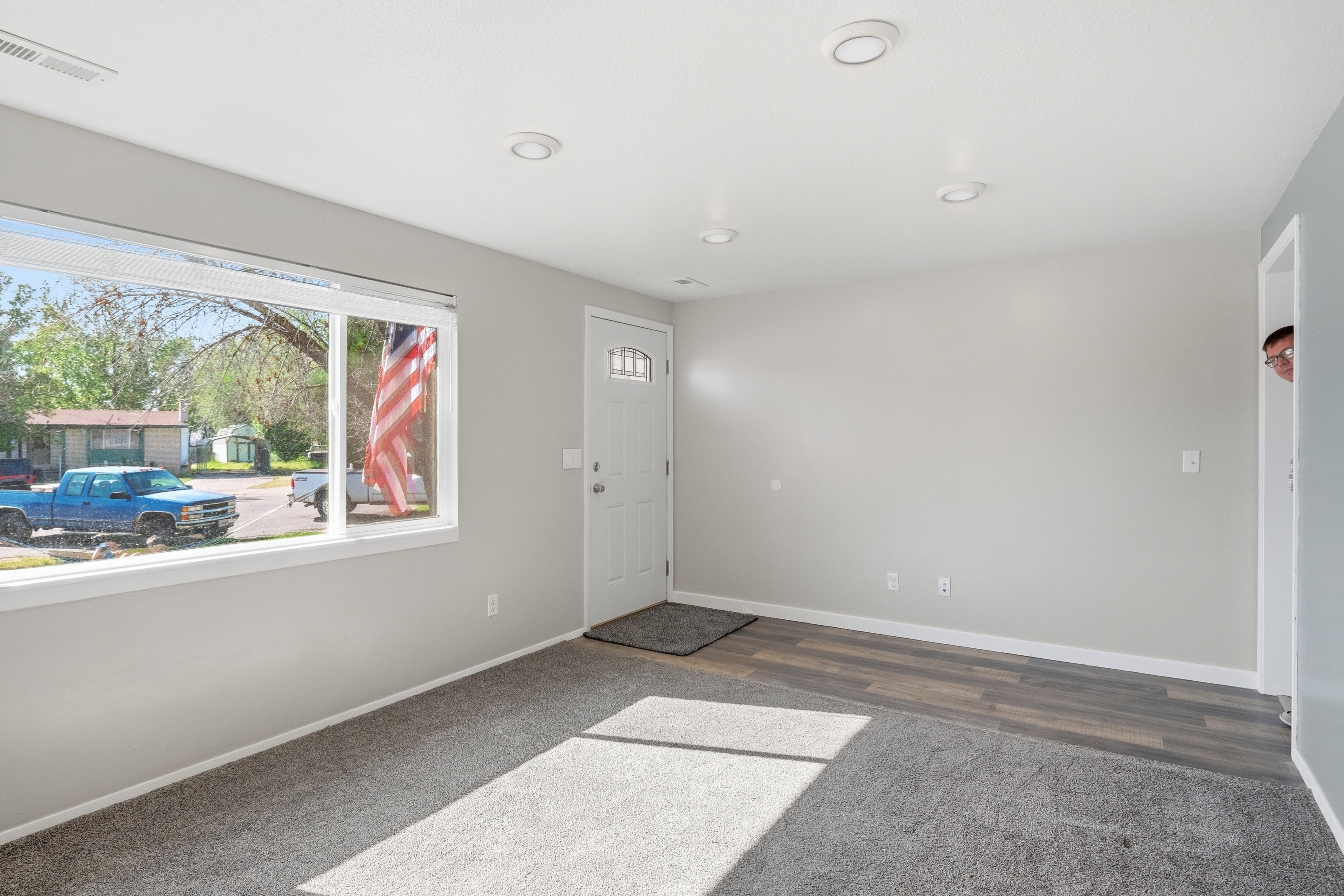 Bright interior space featuring a large picture window, recessed lighting, and a front entry door with decorative glass