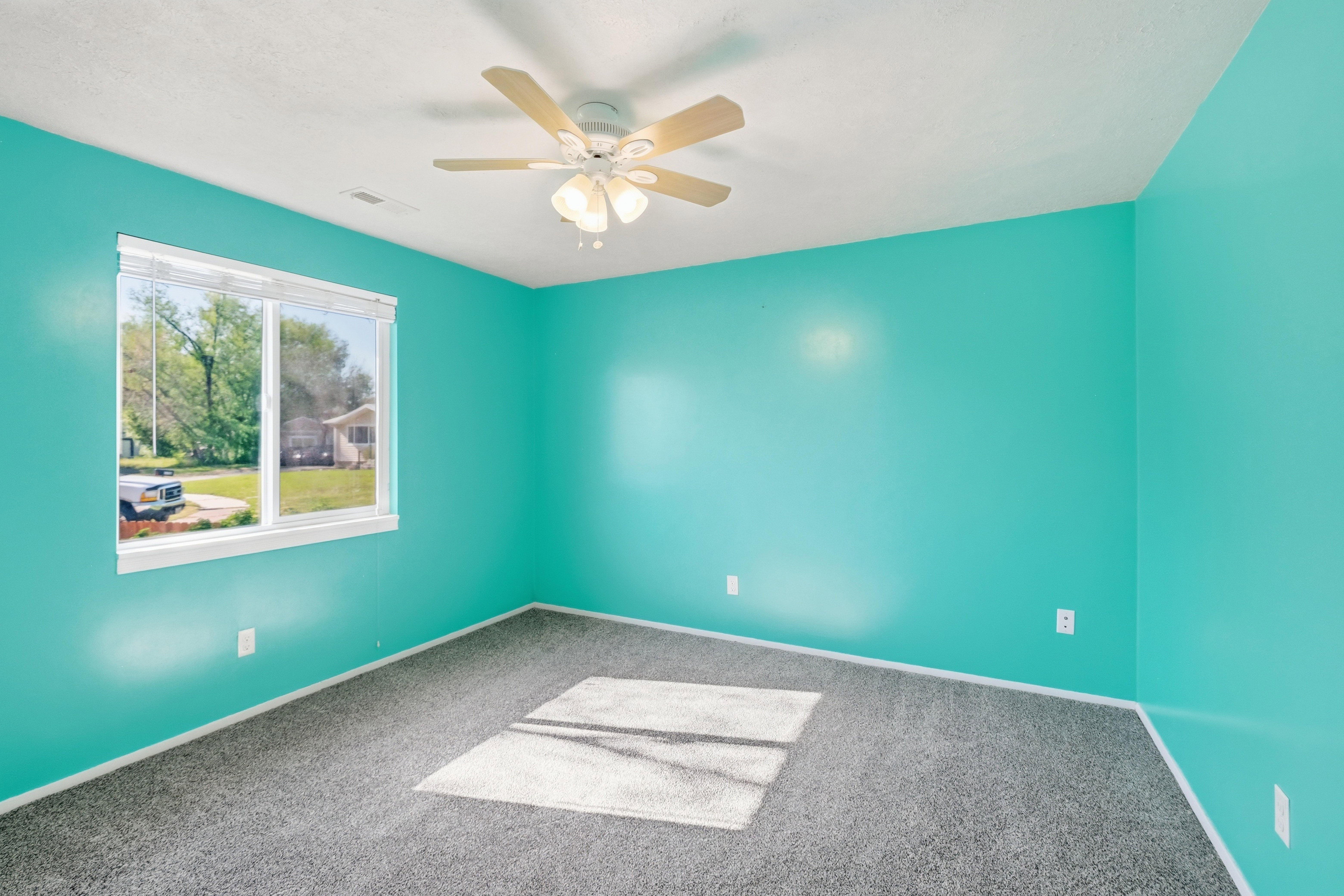 Carpeted room with a ceiling fan light fixture and a large window