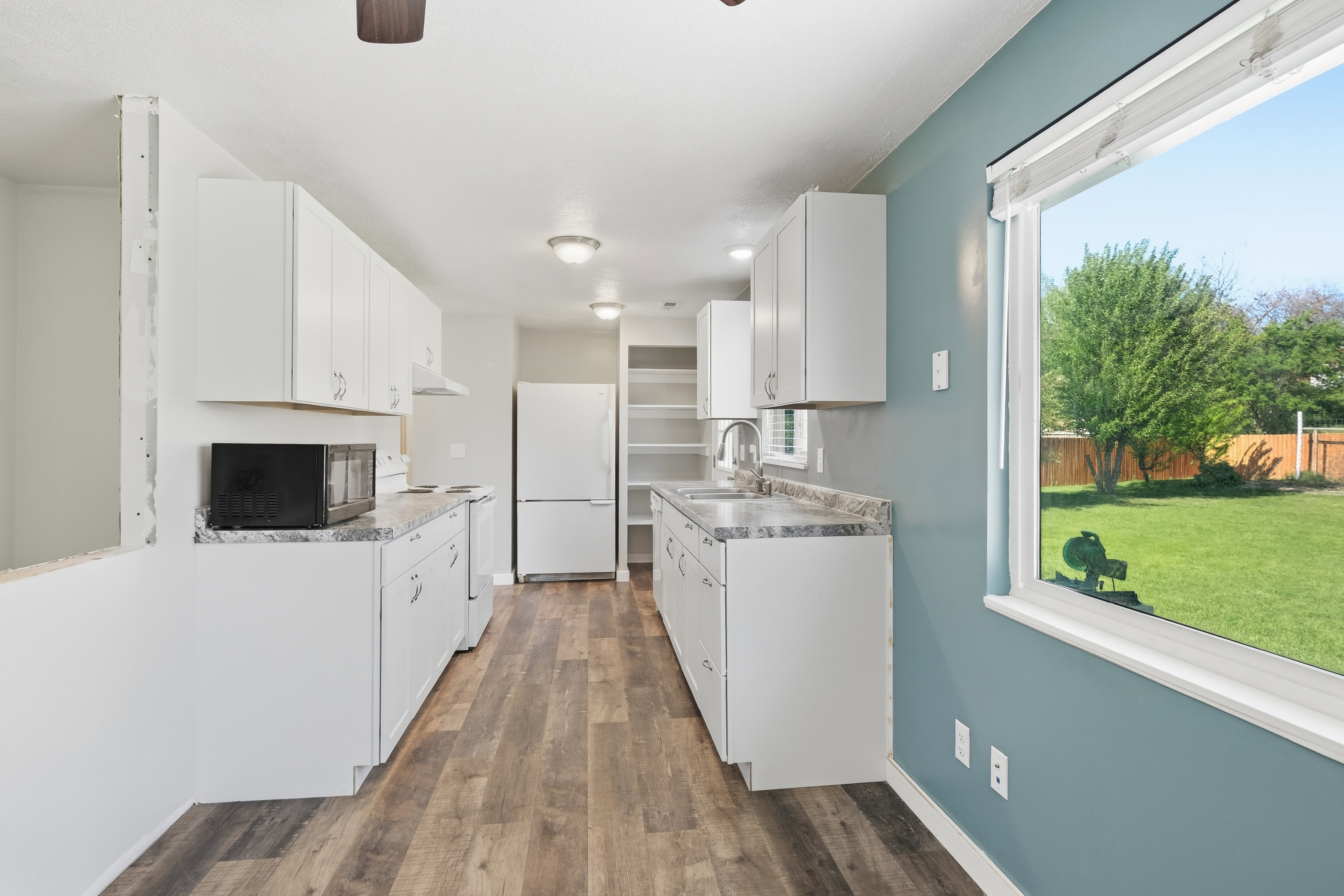 Kitchen featuring white cabinetry, gray patterned countertops, and wood-finish flooring