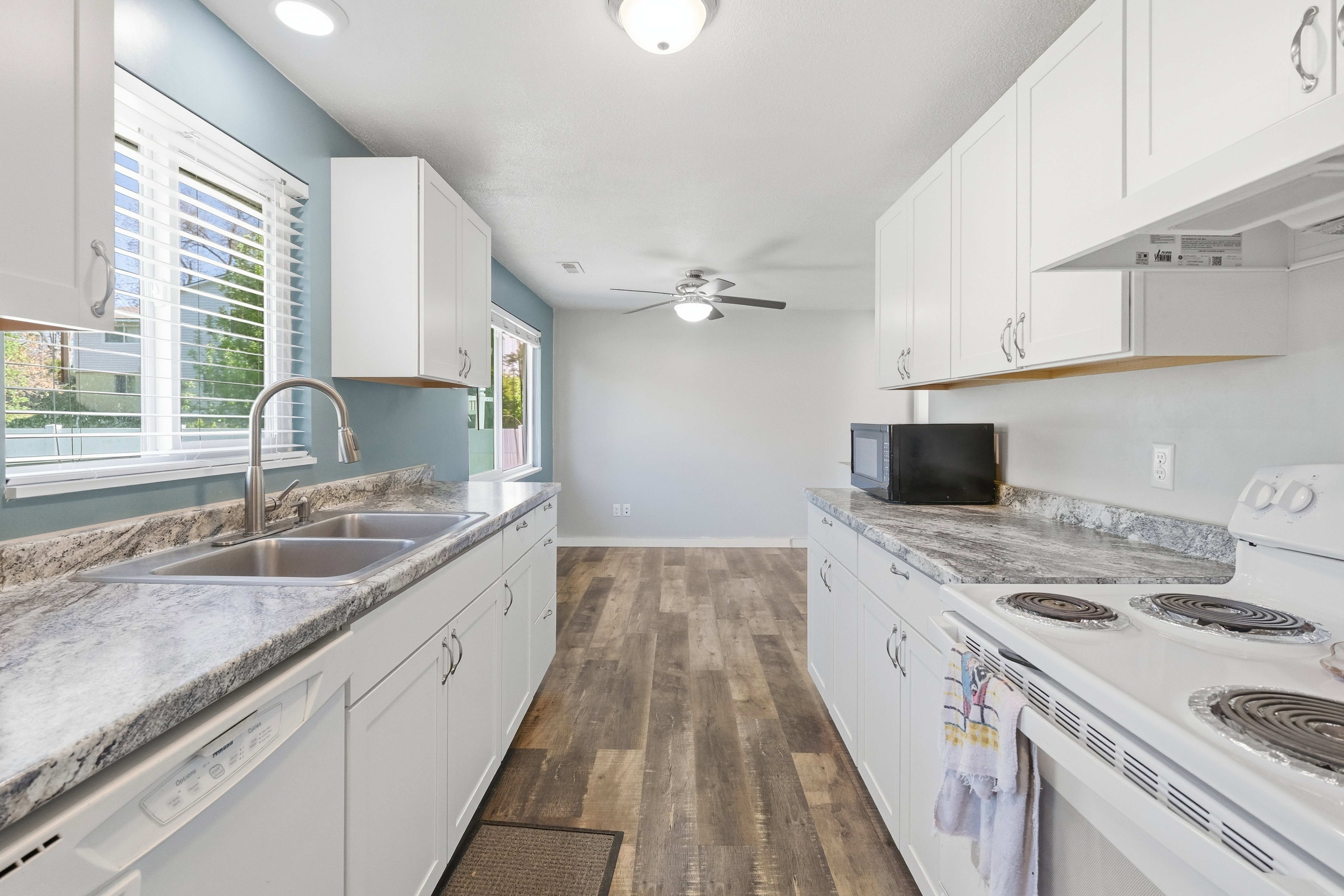 Galley kitchen featuring white cabinetry, light-toned countertops, wood-finish flooring, and recessed lighting