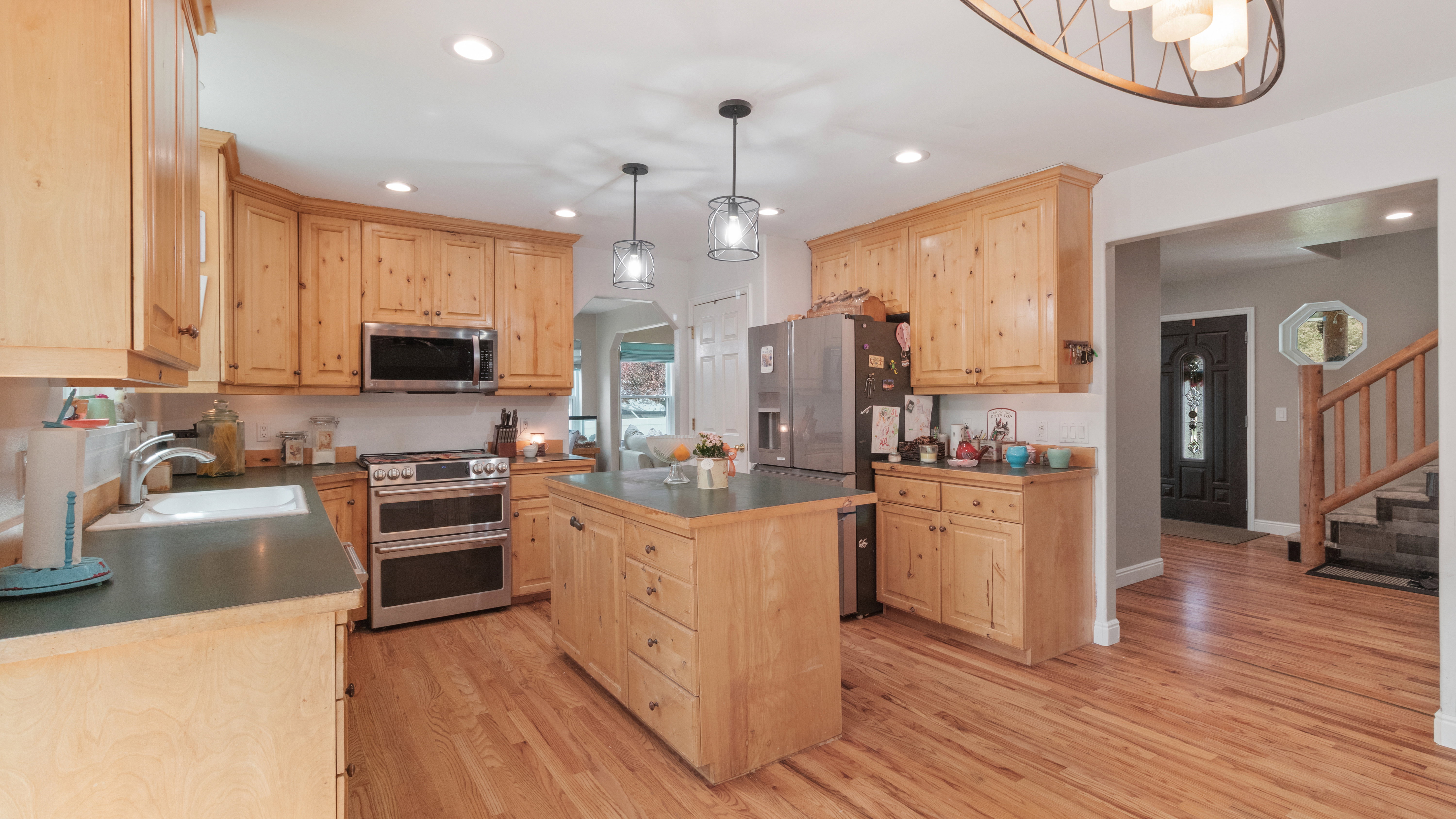 Spacious kitchen featuring wood-finish flooring, custom wood cabinetry, stainless steel appliances, a center island with storage, and recessed lighting