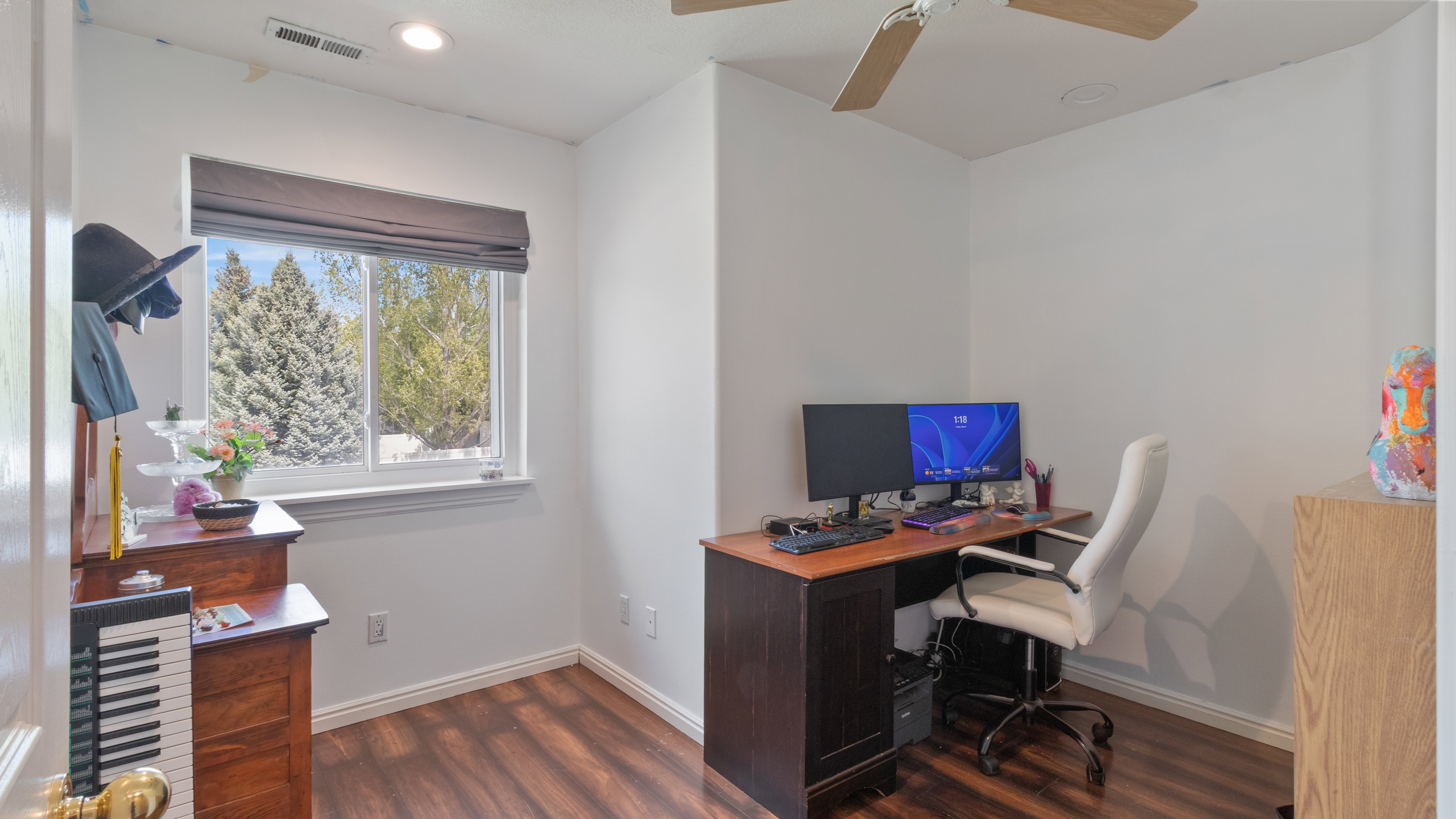 Room featuring a window with a roller shade, wood-finish flooring, a ceiling fan, and recessed lighting