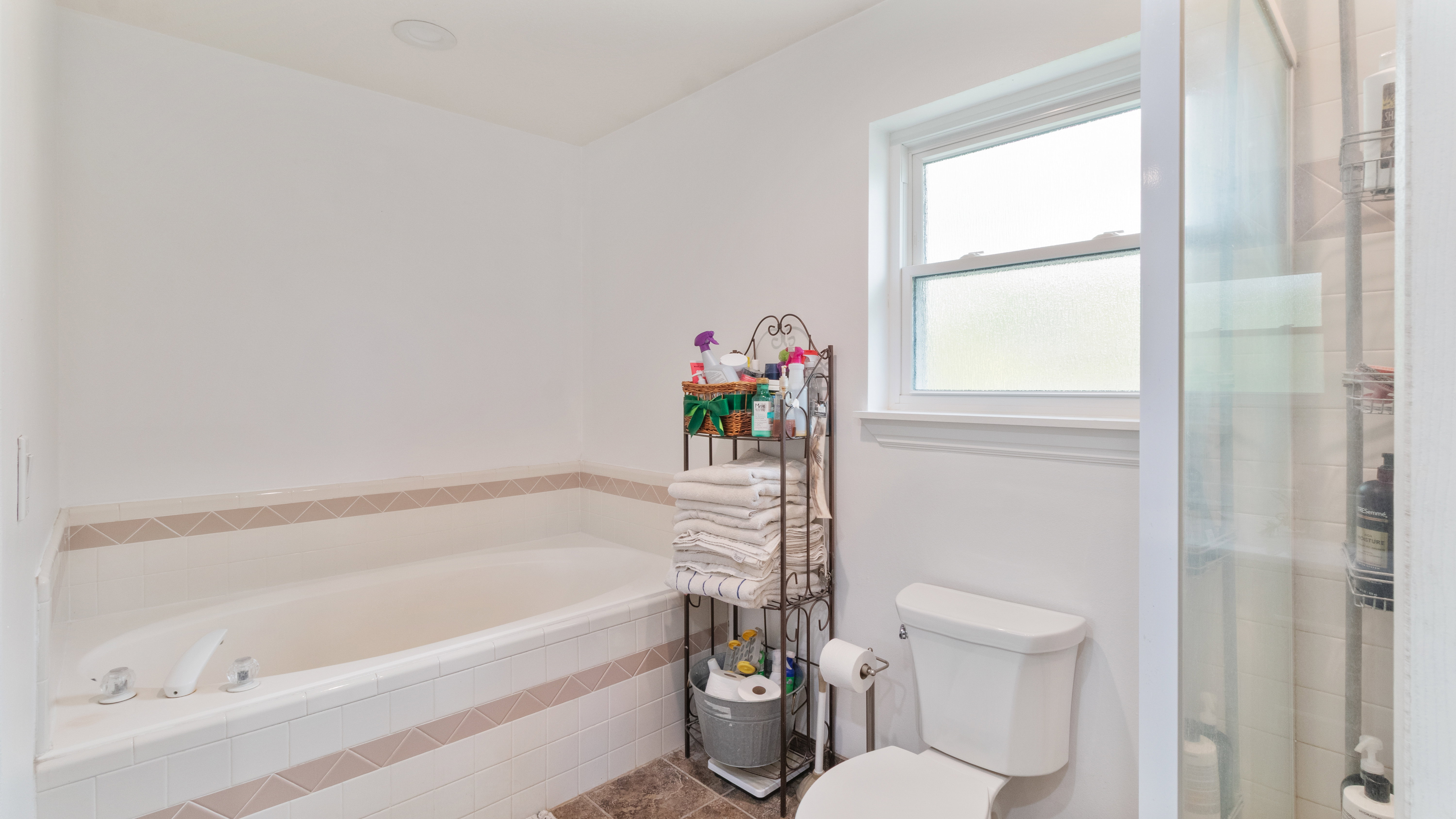 Soaking tub with white surround tiling and decorative tile accent