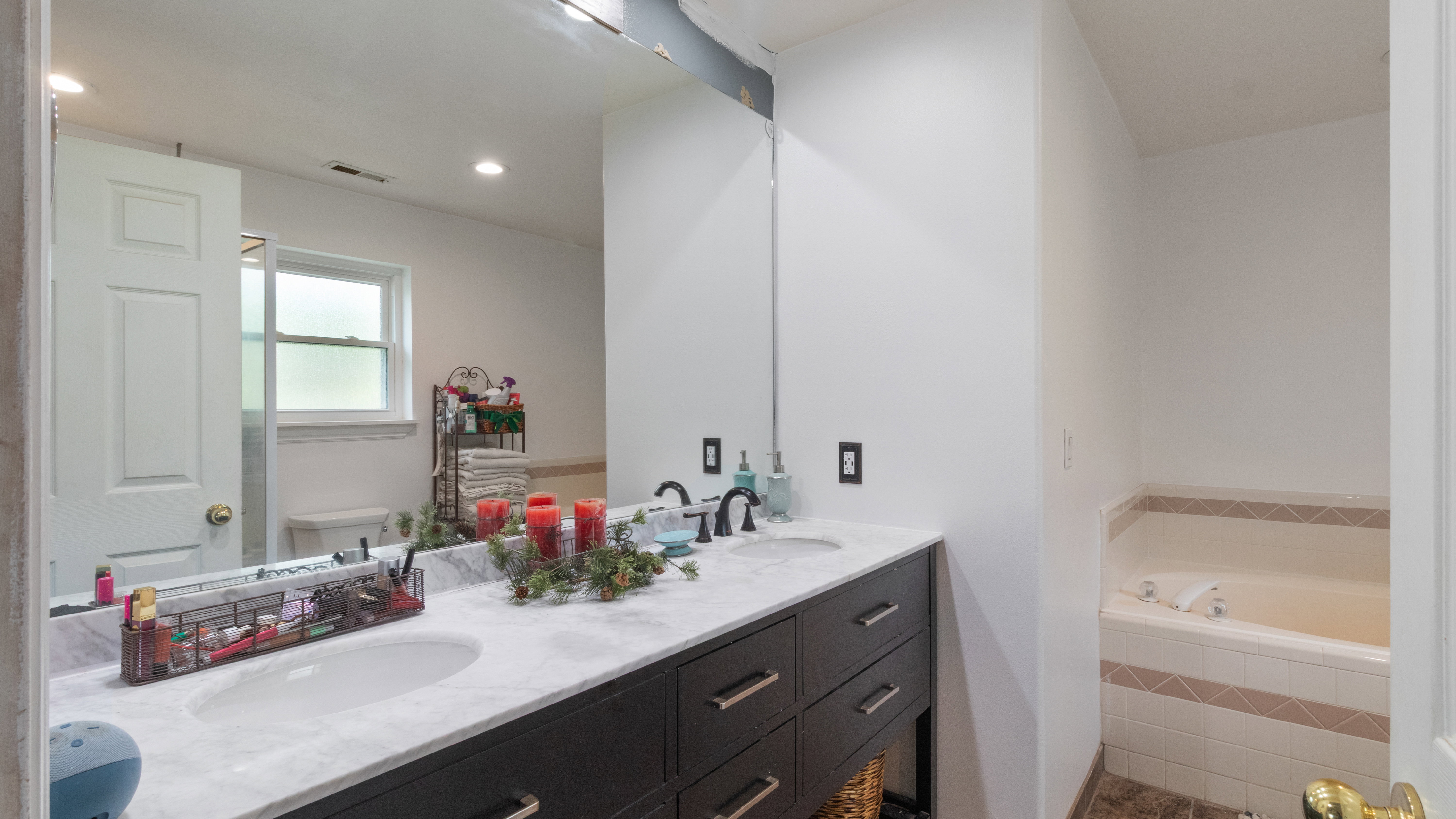 Bathroom featuring a dual-sink vanity with a light-toned countertop, dark wood-finish cabinetry, and black fixtures