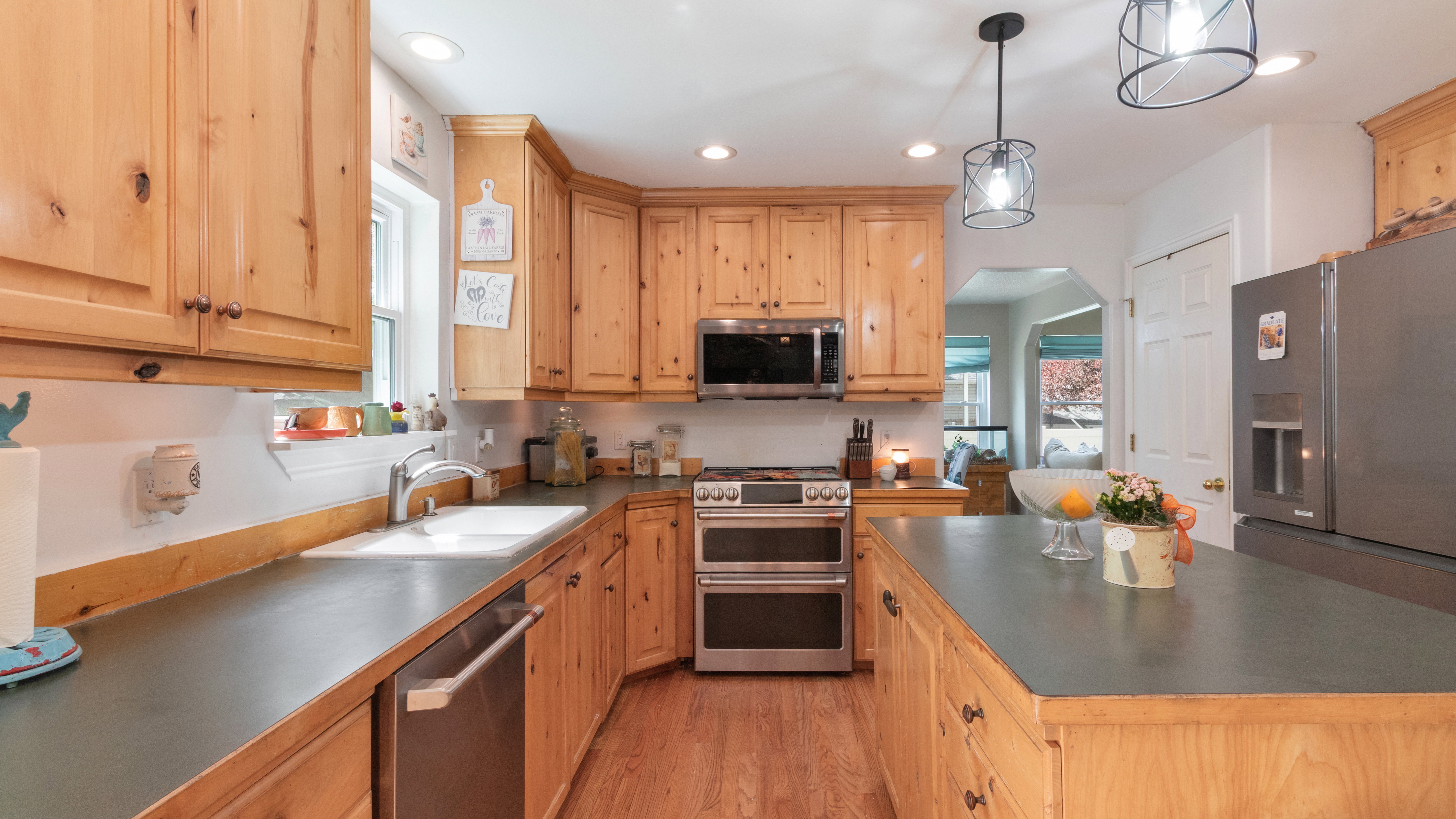 Kitchen featuring knotty pine cabinetry, stainless steel appliances, dark countertops, a central island, and recessed lighting