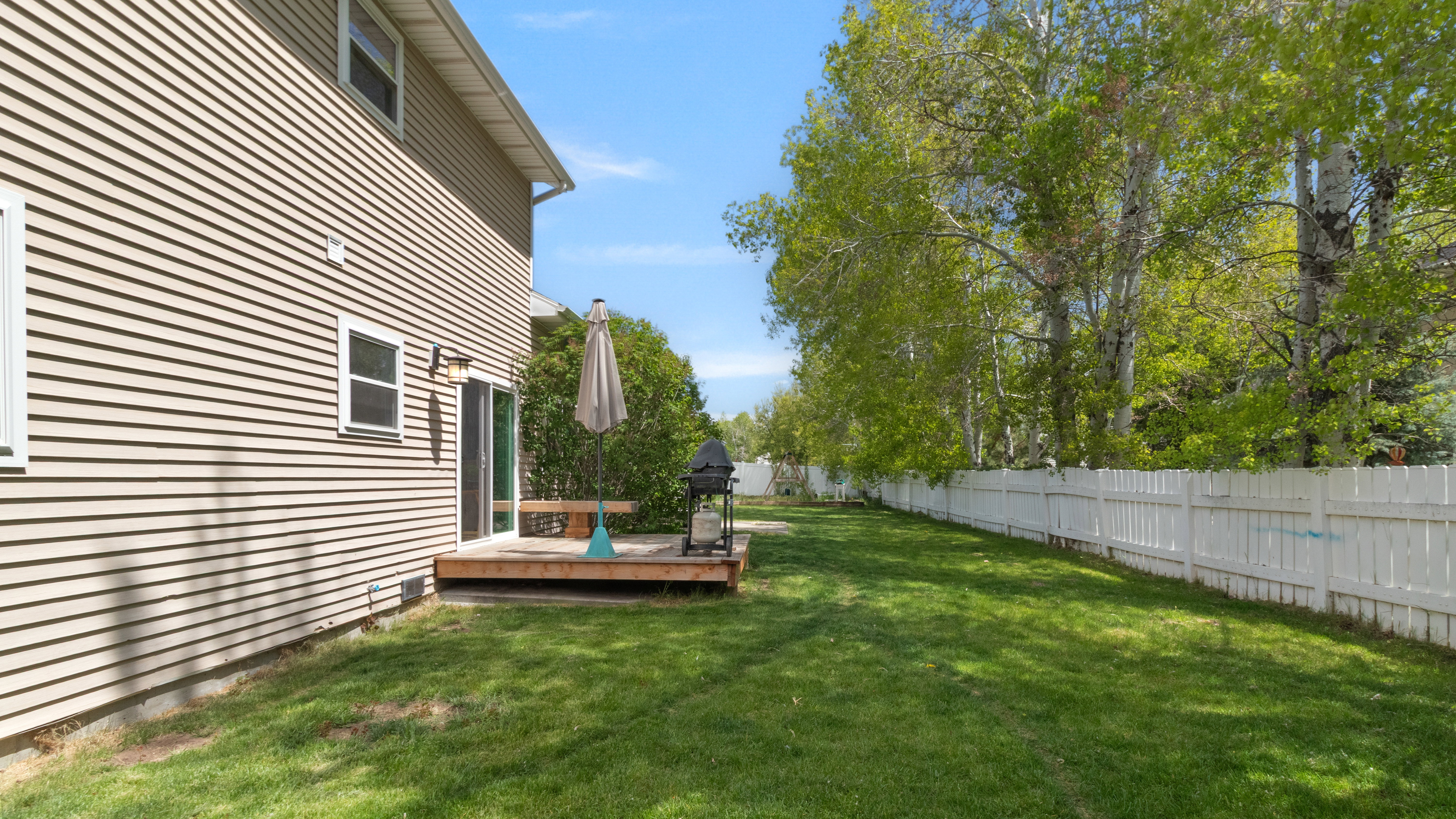 Spacious lawn with a white privacy fence and mature trees