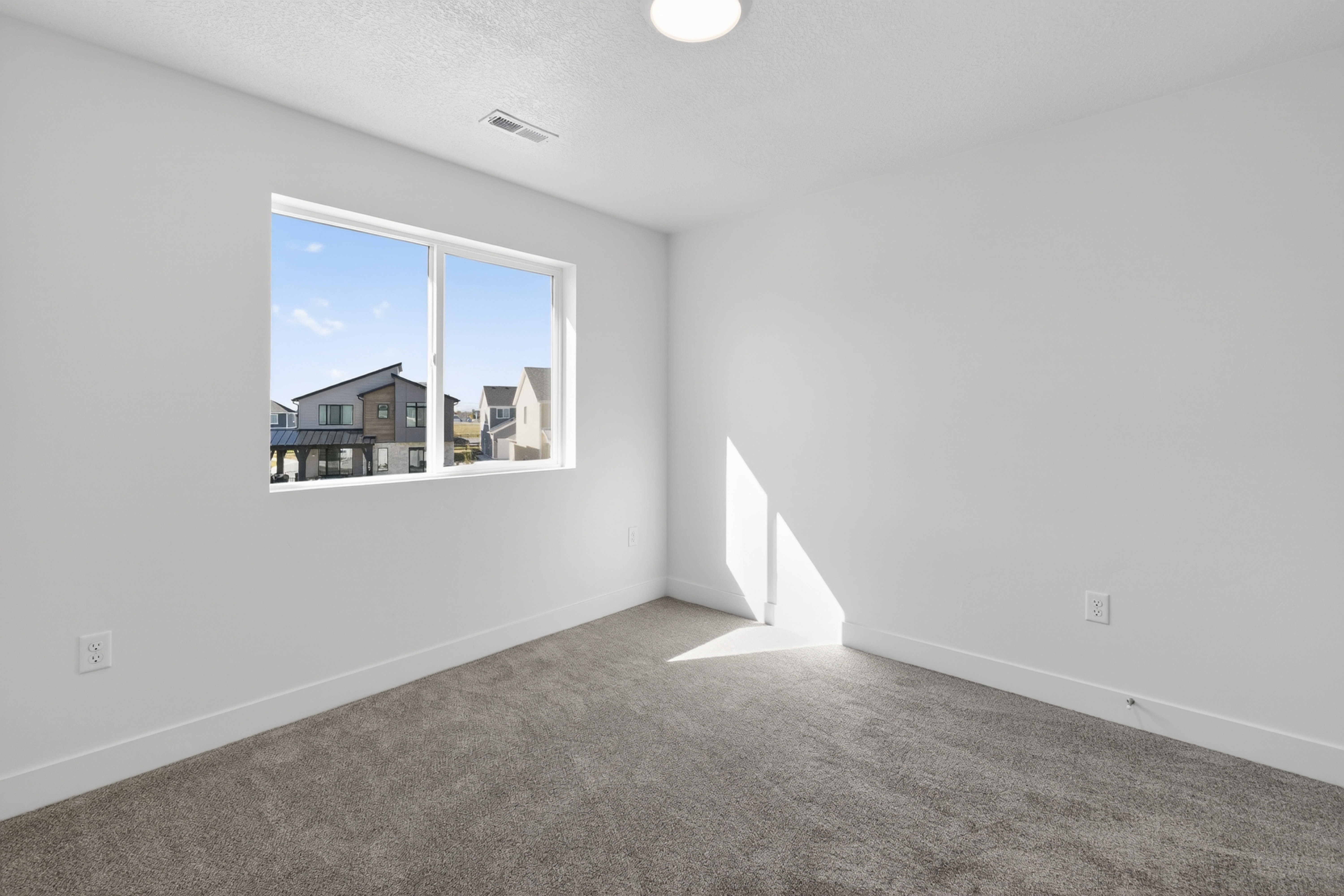 Bright room featuring a large window, neutral carpeting, white walls, and a flush-mount ceiling light