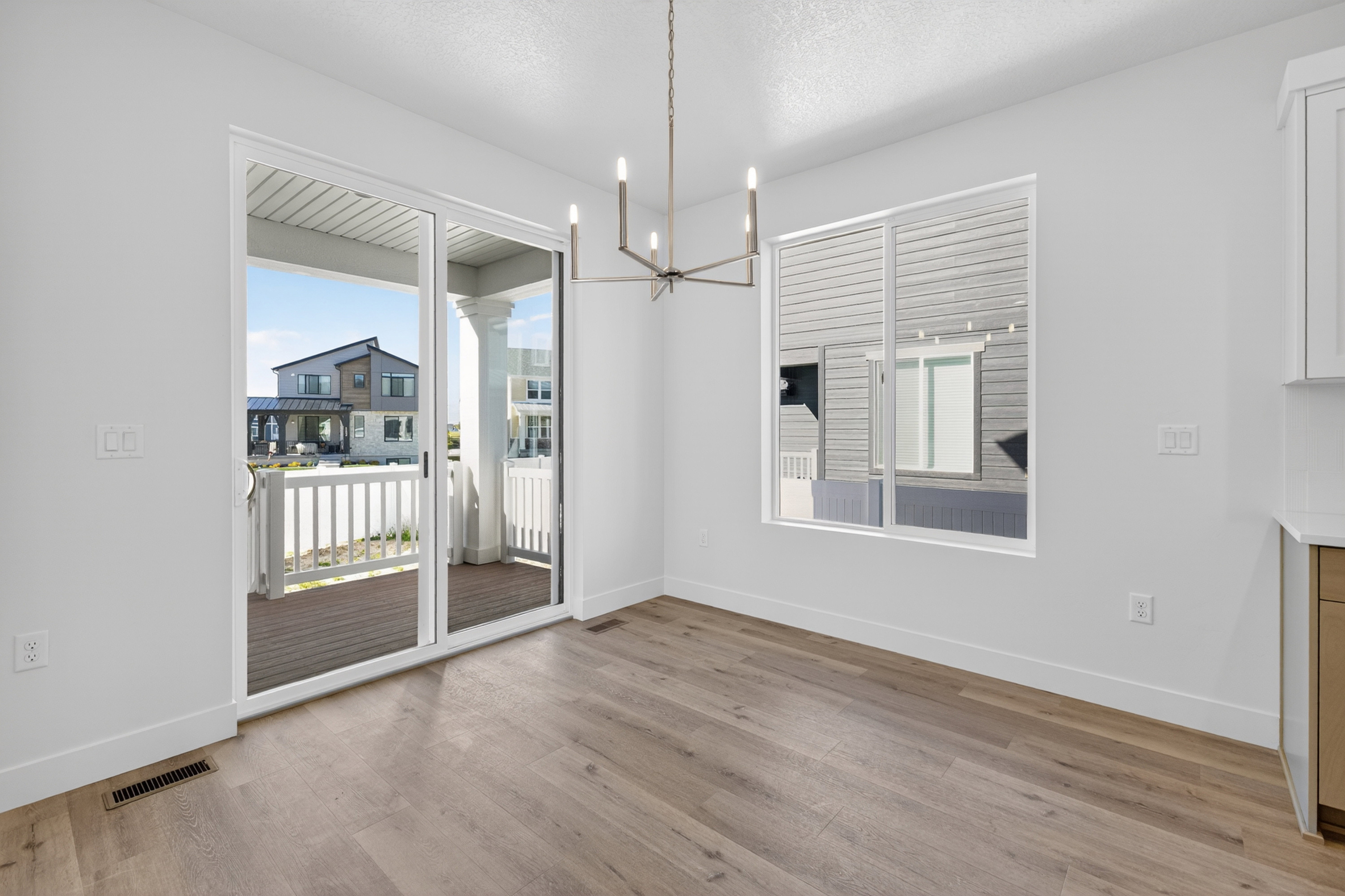 Spacious interior featuring wood-finish flooring, a contemporary chandelier, and white baseboards